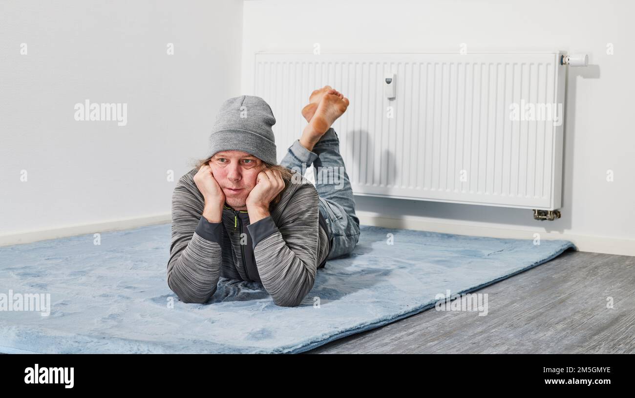 Man lying barefoot in front of heating radiator Stock Photo
