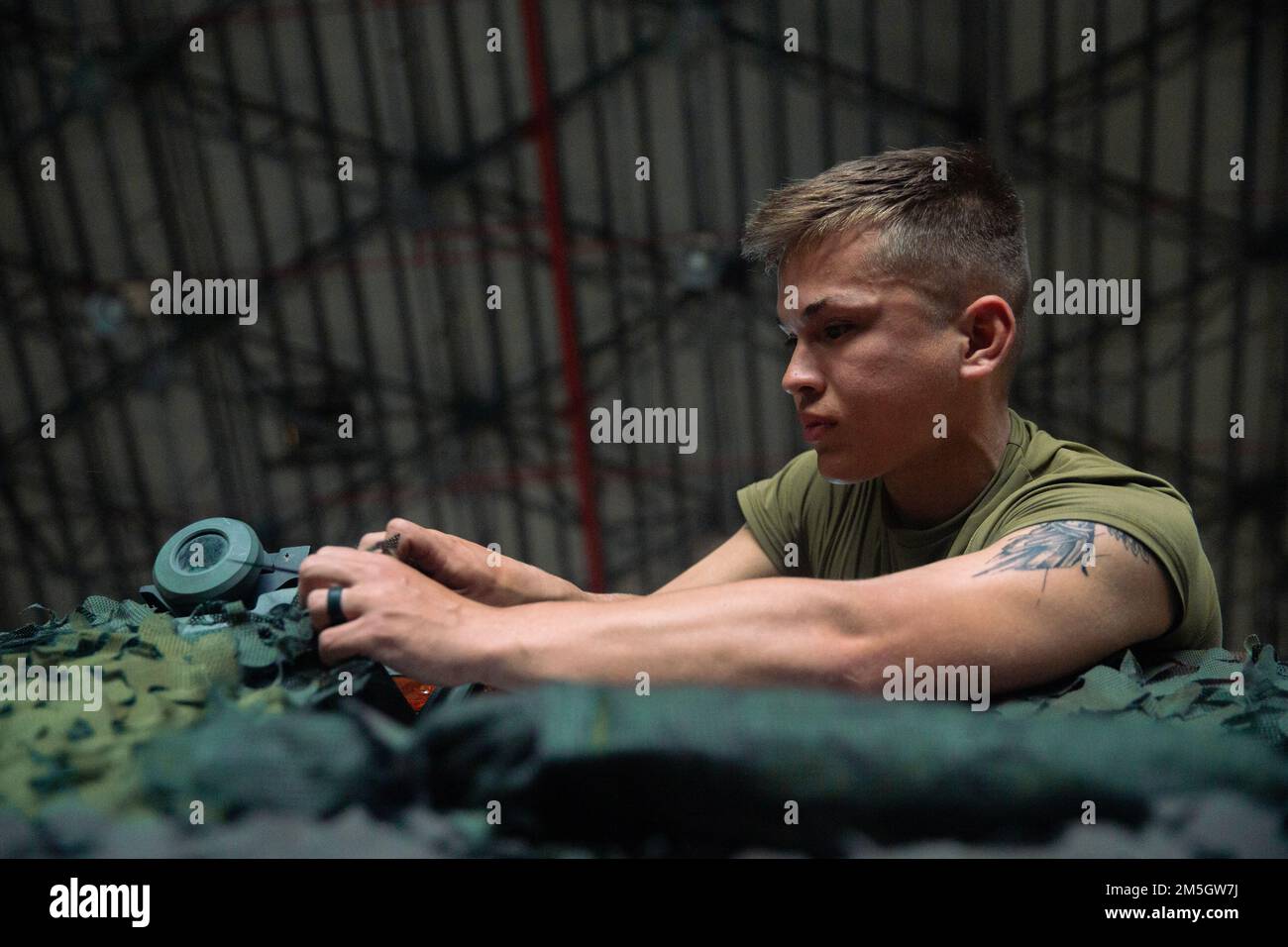 U.S. Marine Corps Cpl. Colin Davis, a High Mobility Artillery Rocket System operator with 3d Battalion, 12th Marines, 3d Marine Division, attaches camouflage netting to a HIMARS launcher prior to a HIMARS Rapid Infiltration mission on Iwo Jima, Japan, during exercise Typhoon Crossbow, March 17, 2022. This exercise demonstrated 3d Marine Division’s ability to quickly deploy long range precision fires to key maritime terrain across the Indo-Pacific region. Stock Photo