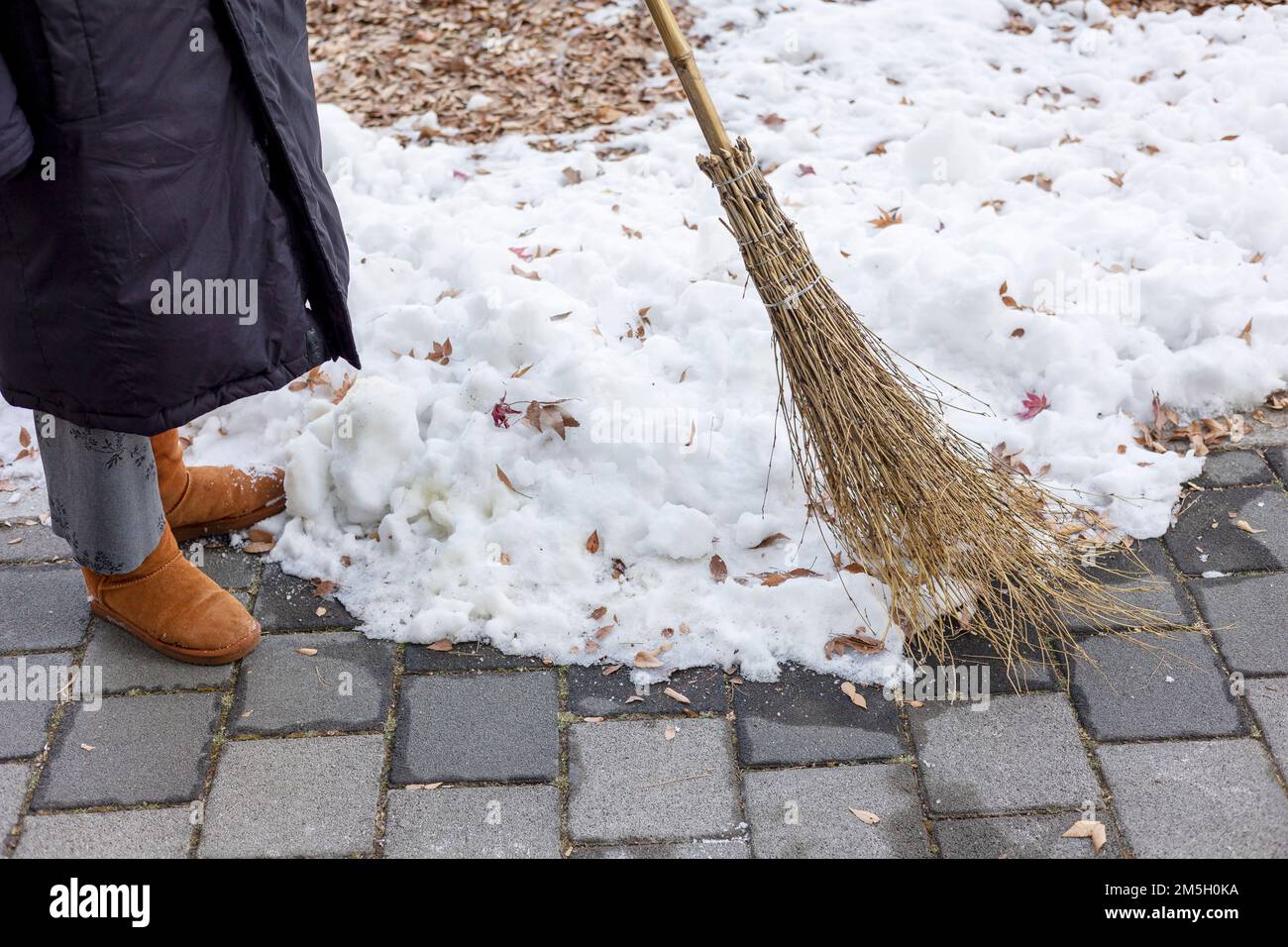 Woman is sweeping snow with a broom in winter Stock Photo Alamy