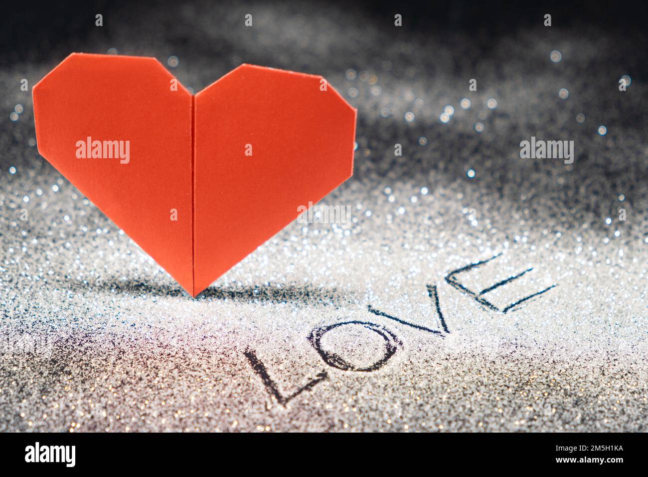 Happy Valentine's Day, red heart on a black snow-covered shiny background, text love Stock Photo