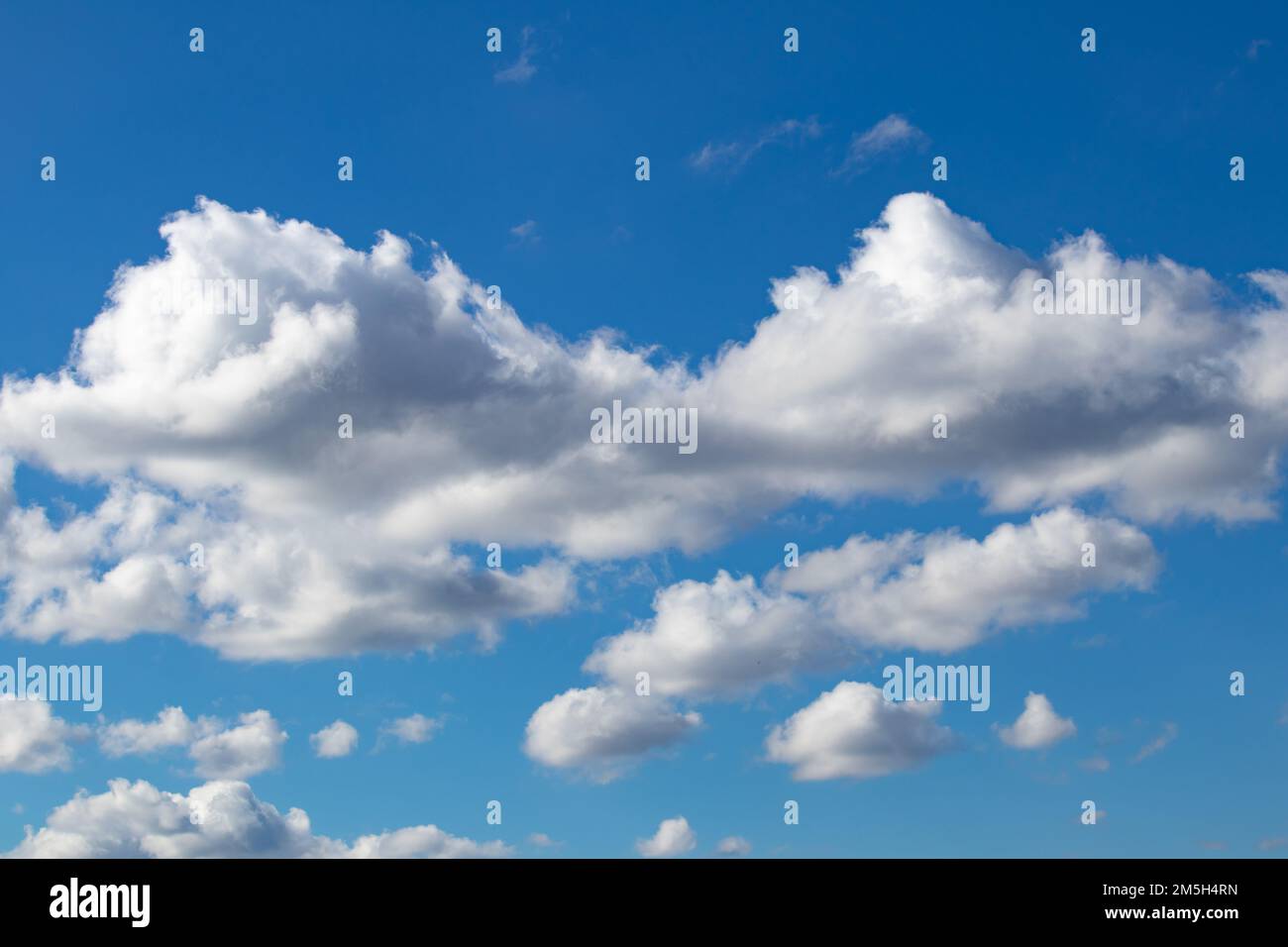 Cloudy blue sky, white clouds background with deep blue sky. Wallpaper with sunlight. Texture, pattern idea concept. Horizontal photo. No people. Stock Photo