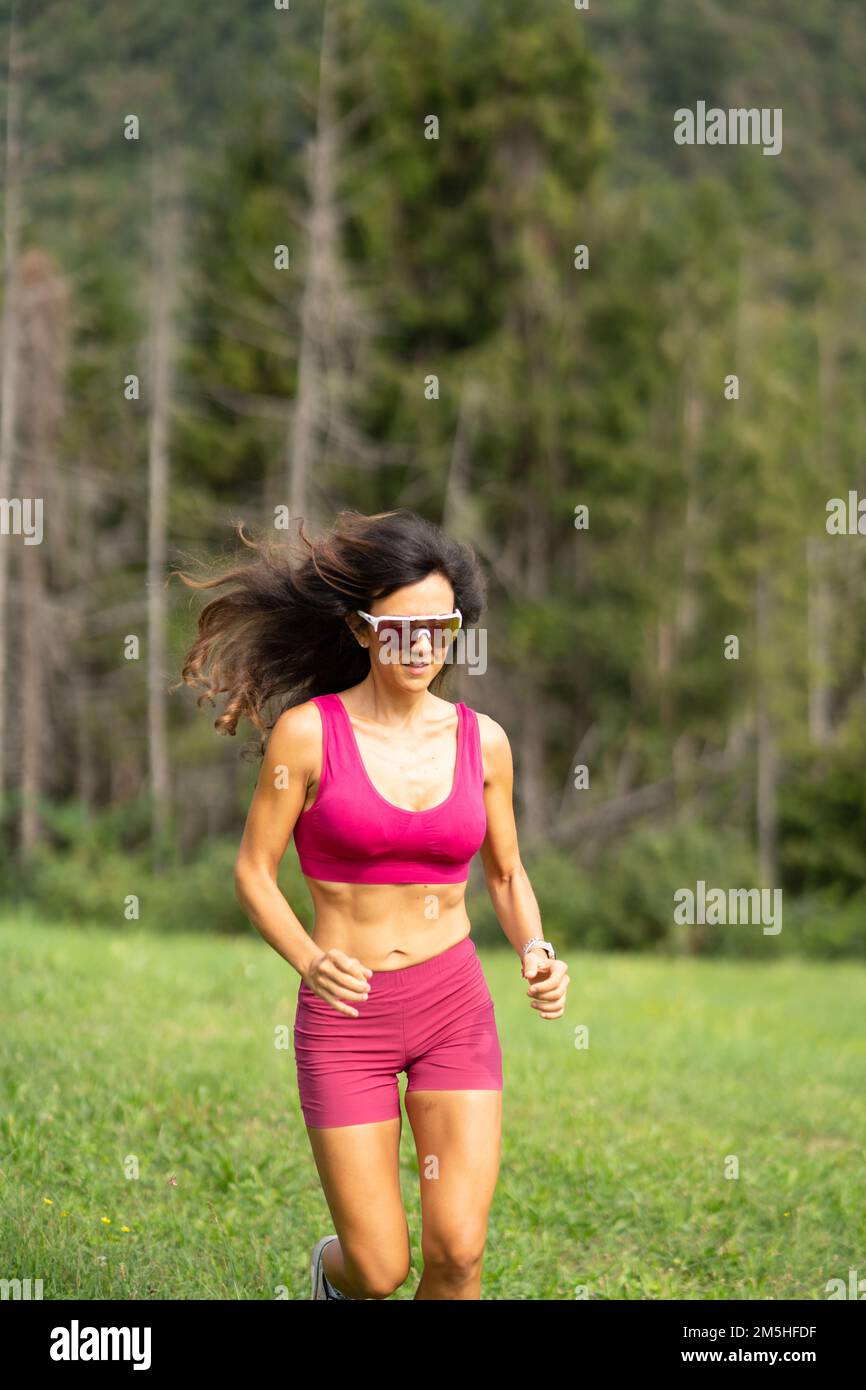 Trail running smiling girl runs uphill and on meadow Stock Photo Alamy