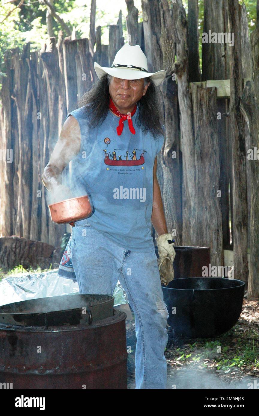 Cherokee Hills Byway - Cherokee Gentleman Cooking Traditional Food. A typical hog fry is done on special occasions. Tradition continues today as a Cherokee man, dressed in jeans, a t-shirt, a cowboy hat, and a bandanna, is cooking pork in the big black kettles over an open fire. Location: Oklahoma Stock Photo