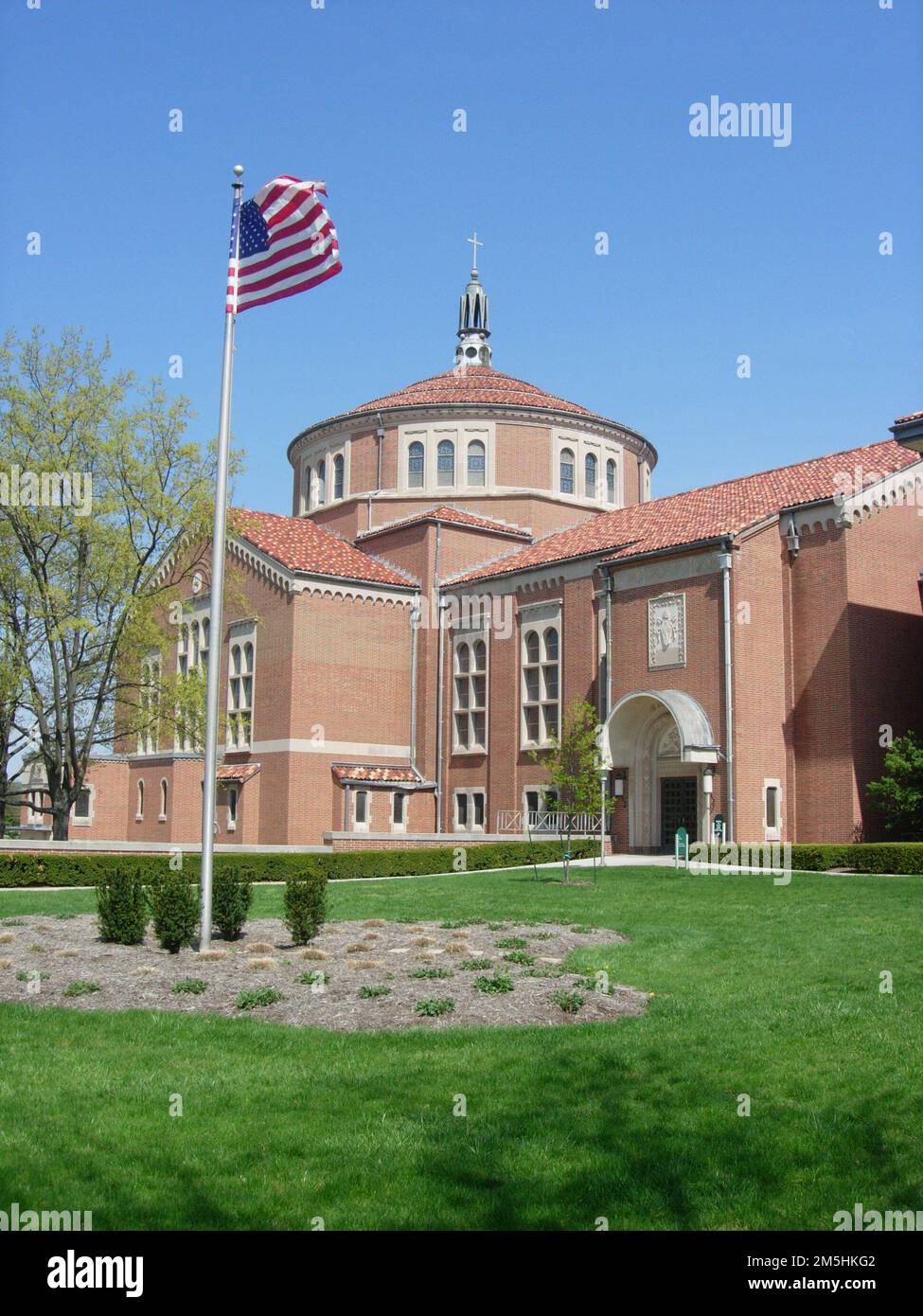 Journey Through Hallowed Ground Byway - A Cloudless Sky Over the Shrine of Saint Elizabeth Ann Seton. The imposing architecture of the Shrine of Saint Elizabeth Ann Seton is impressive red brick and includes a basilica, offices, and several wings surrounded by wide green lawns and a high-flying US flag. Stock Photo