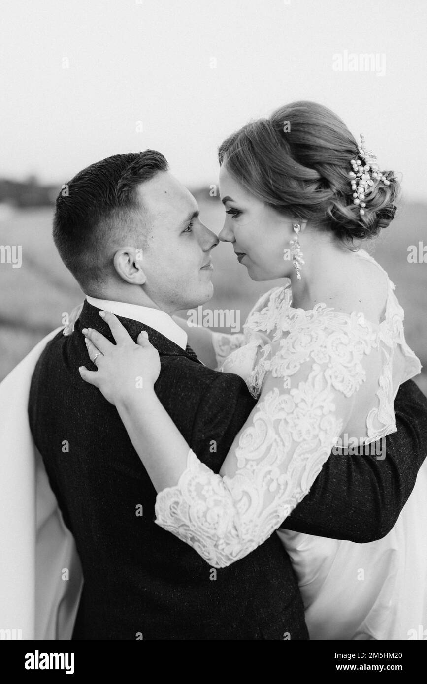 the groom and the bride walk along the wheat green field on a bright
