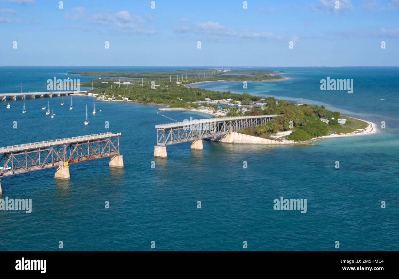 Florida Keys Scenic Highway - Bahia Honda State Park. The aerial view of Bahia Honda State Park, FL, reveals the span of white, sandy beach on the Atlantic side-winding around the historic railroad bridge and sailboats moored into the bay, with the modern Florida Keys Scenic Byway and the Gulf of Mexico to the north. Location: Bahia Honda State Park, Florida (24.655° N 81.283° W) Stock Photo