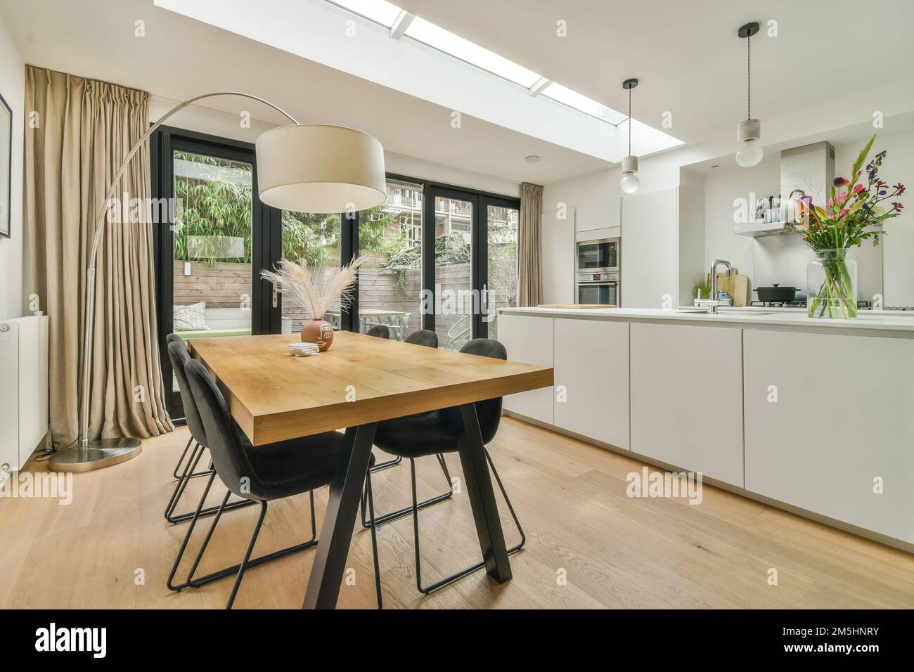 a dining room with wood flooring and skylights above the kitchen area ...