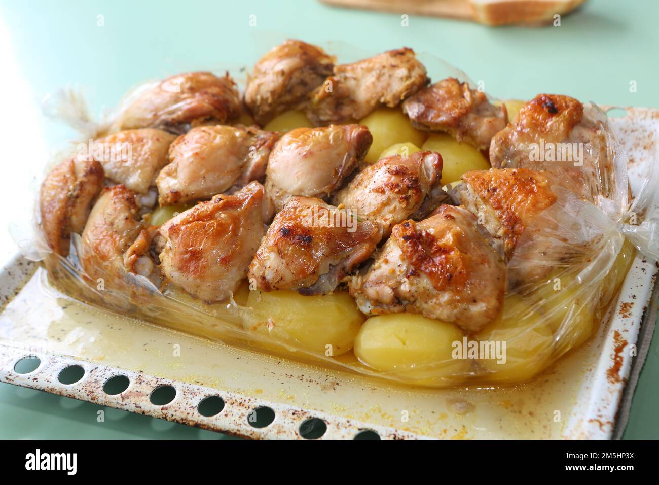Freshly baked chicken wings with marble potatoes on a baking pan Stock Photo