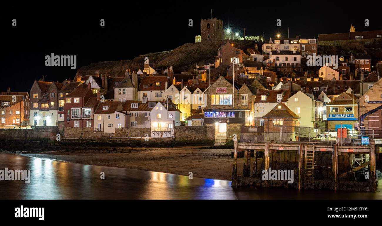 The lights of Whitby old town reflected in the calm waters of the harbour Stock Photo