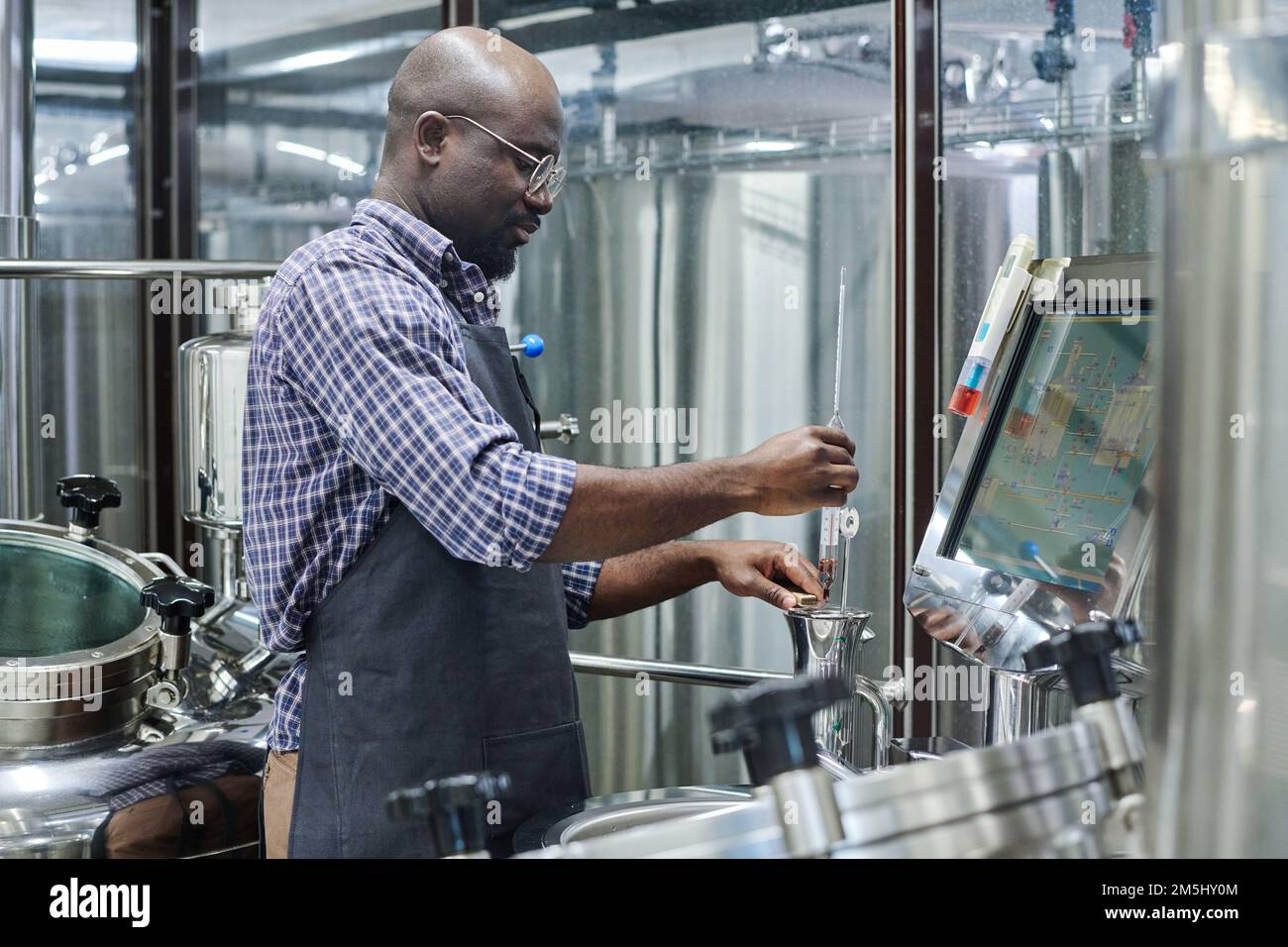African American engineer controlling the equipment for brewing beer