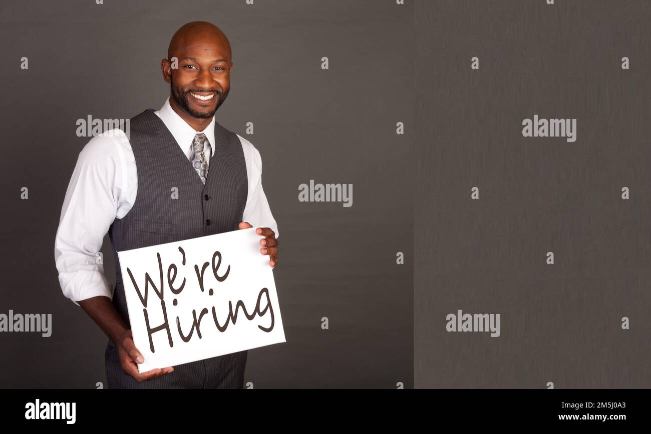 Young Black Business Man holding Were Hiring Sign Stock Photo Alamy
