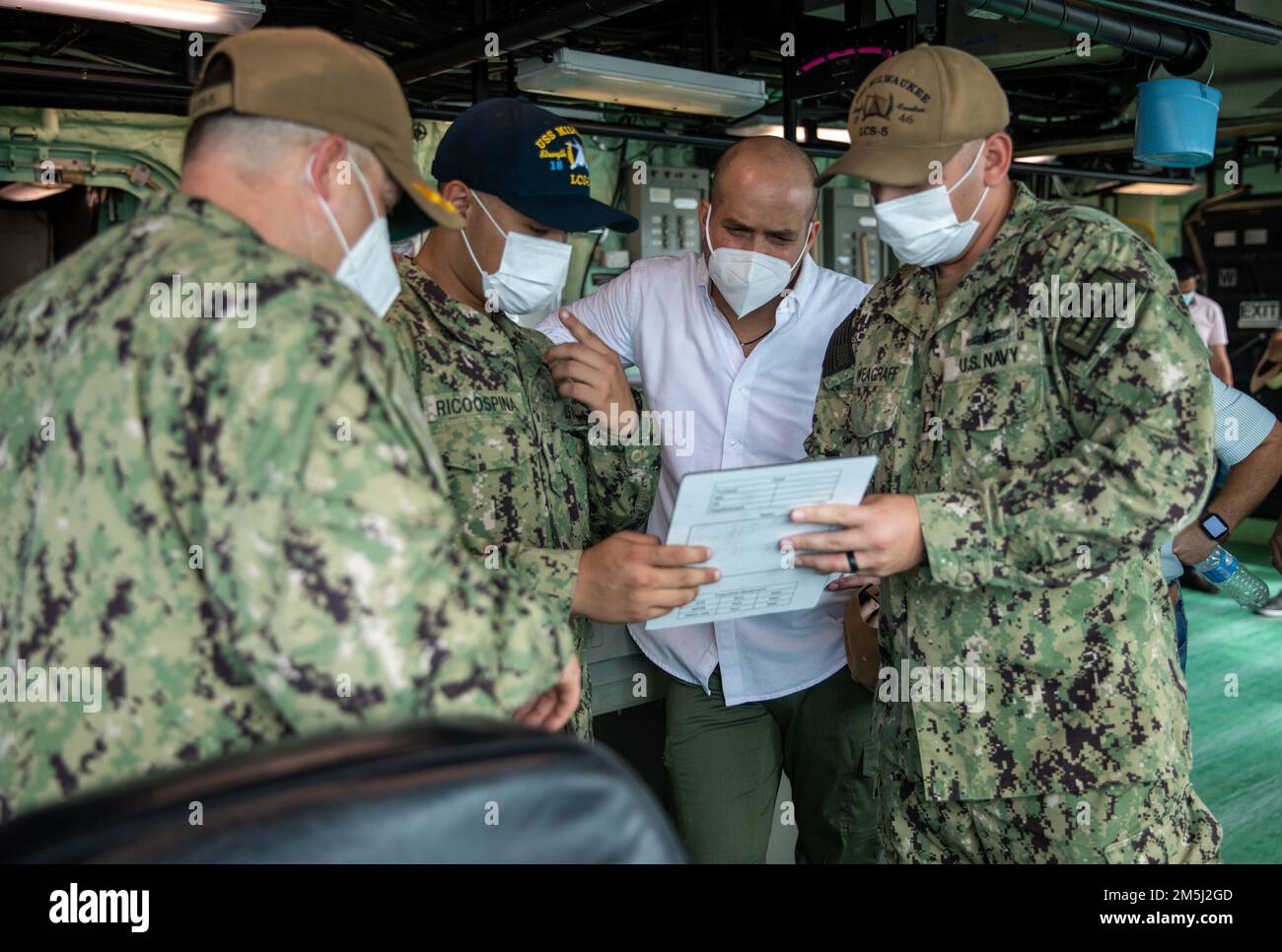 220318-N-HD110-1211  MANTA, Ecuador - (March 18, 2022) -- Lt. Logan Weagraff, right, assigned to the Freedom-variant littoral combat ship USS Milwaukee (LCS 5), reads off a pilot card while Aviation Machinist’s Mate 3rd Class Felix Ricoospina, assigned to the “Sea Knights” of Helicopter Sea Combat (HSC) Squadron 22, Detachment 5, translates in Spanish to Agustín Quijano, mayor of Manta, in the pilot house during Quijano’s visit to the ship, March 18, 2022. Milwaukee is deployed to the U.S. 4th Fleet area of operations to support Joint Interagency Task Force South’s mission, which includes coun Stock Photo