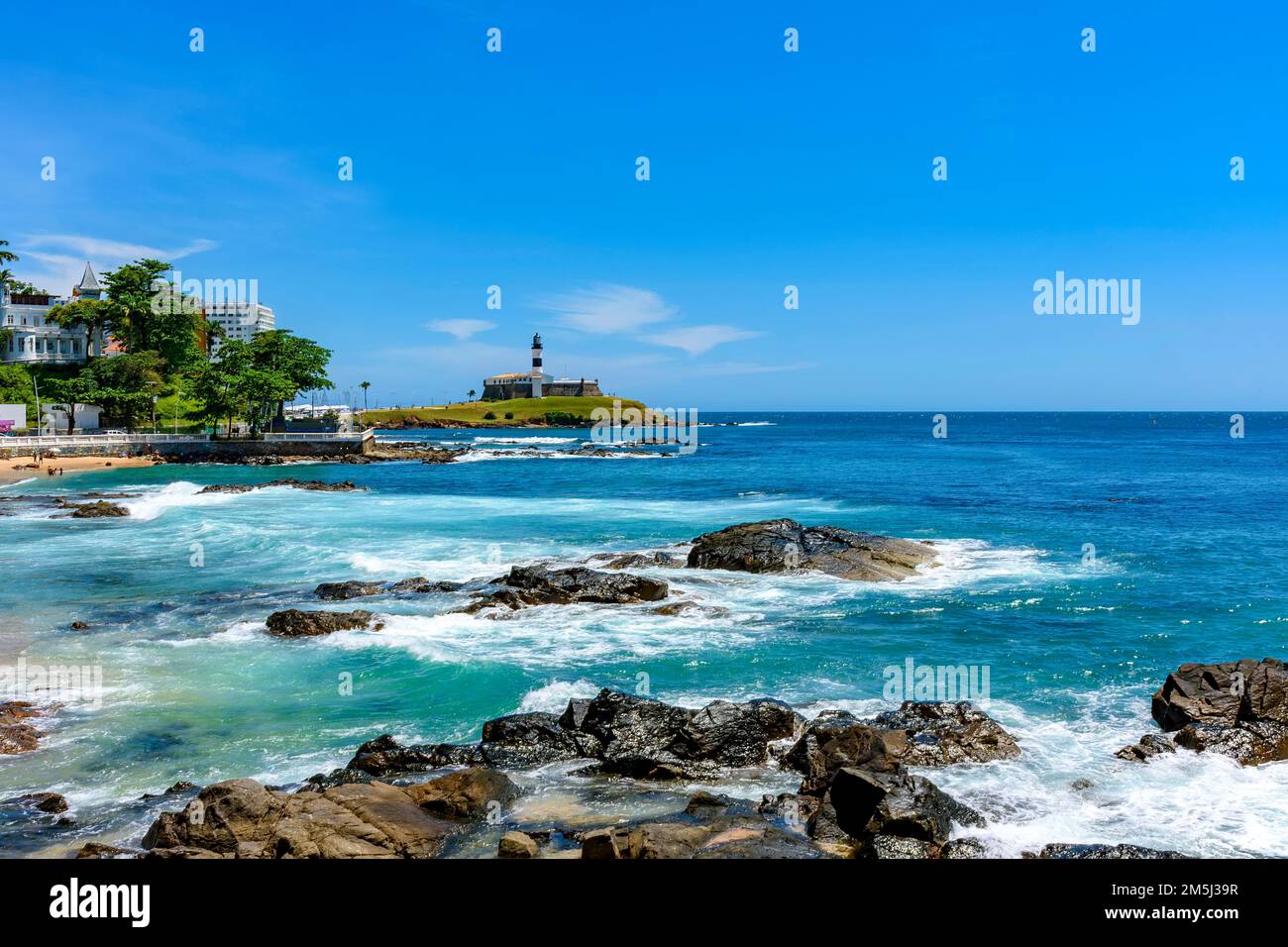 The sea of the city of Salvador in Bahia and the famous Barra lighthouse in a sunny day Stock Photo