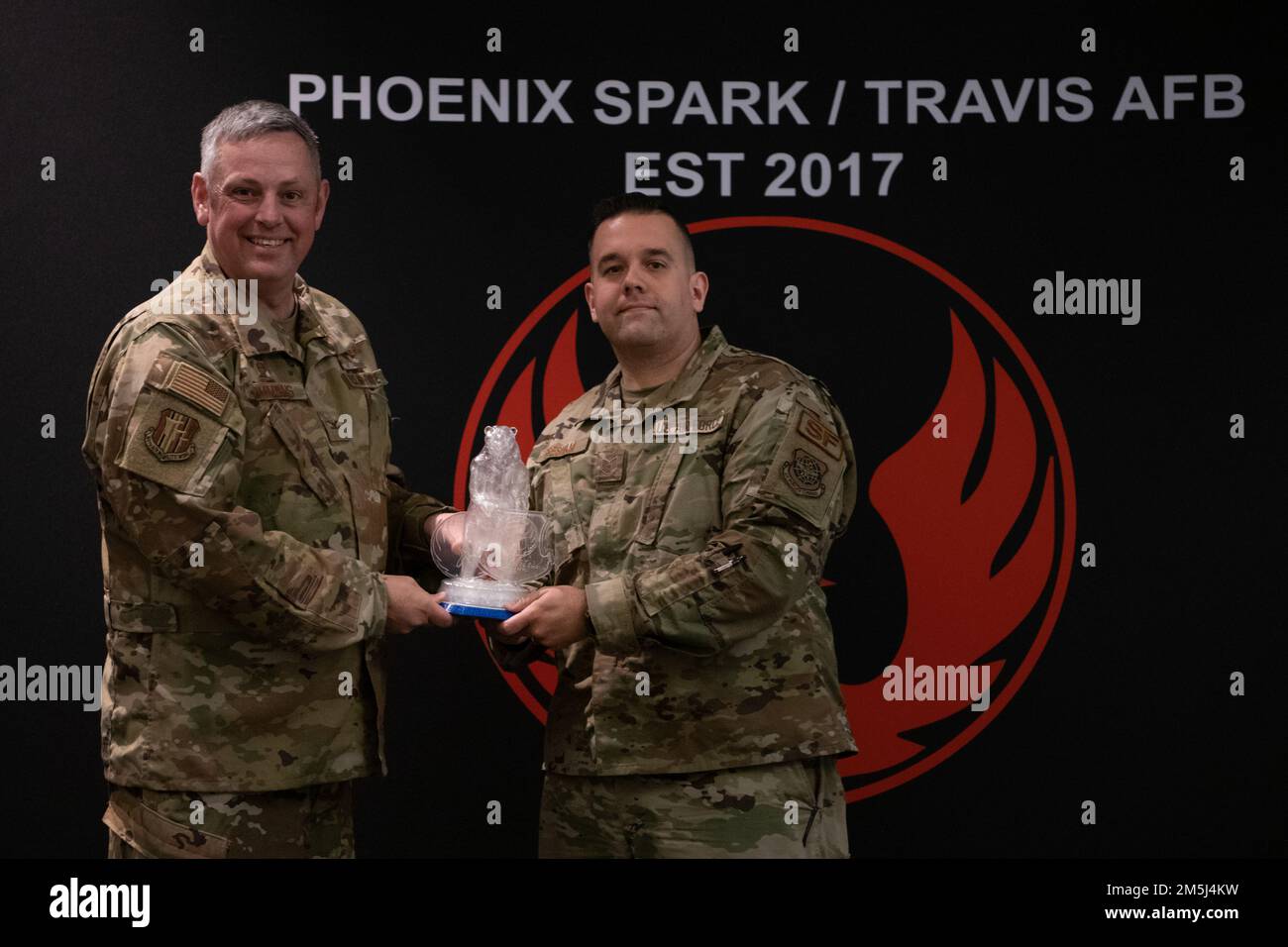 U.S. Air Force Col. Corey Simmons, 60th Air Mobility Wing commander, presents the 2022 Golden Bear Travis Air Force Base Impact Award to Tech. Sgt. Donald Gresham, 60th Security Forces Squadron noncommissioned officer in charge of the access control section, at Travis AFB, California, March 18, 2022. Phoenix Spark hosted the Travis AFB Spark Tank 2022. It recognized the top six finalists from a field of 55 ideas submitted by Travis Airmen to the inaugural Squadron Innovation Funds Sparks Tank. The ideas varied from a six-figure software system to simple purchases of off-network machines. Stock Photo