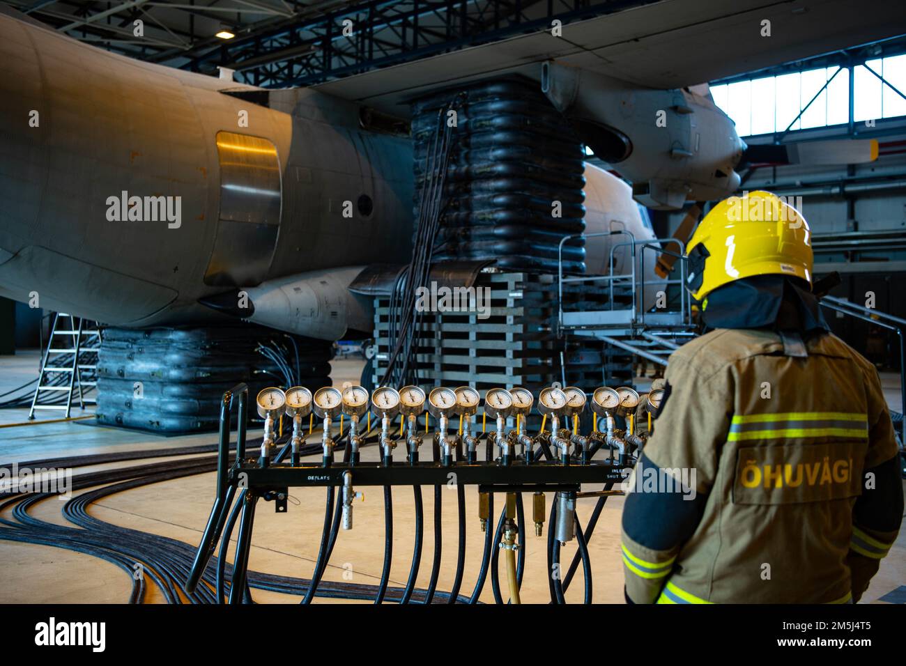 An Estonian air force firefighter watches as a G-222 aircraft is lifted during the Crashed Damaged Disabled Aircraft Recovery exercise at Ramstein Air Base, Germany, Mar. 22, 2022. The training focused on properly storing, inspecting, maintaining, and operating CDDAR equipment. Stock Photo