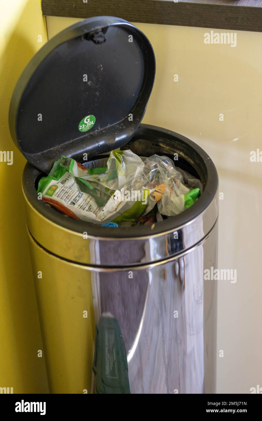 Stainless steel flip lid bin full to the brim with rubbish Stock Photo