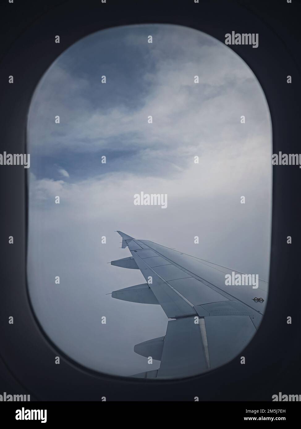 Plane flight through the dense foggy clouds. Airplane wing seen through the window Stock Photo