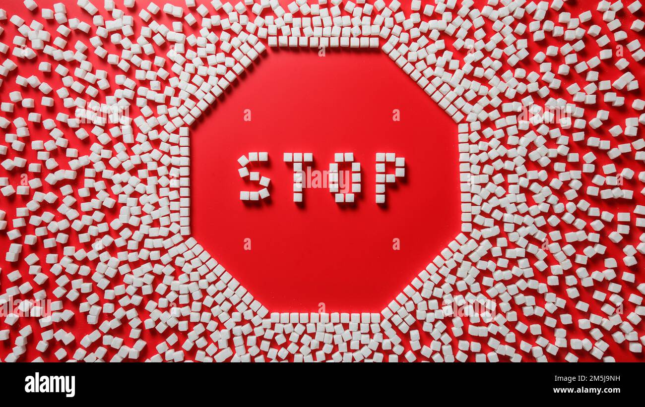 octagonal frame in the form of a stop sign made of sugar cubes with red background and word stop inside. stop eating refined sugar concept Stock Photo