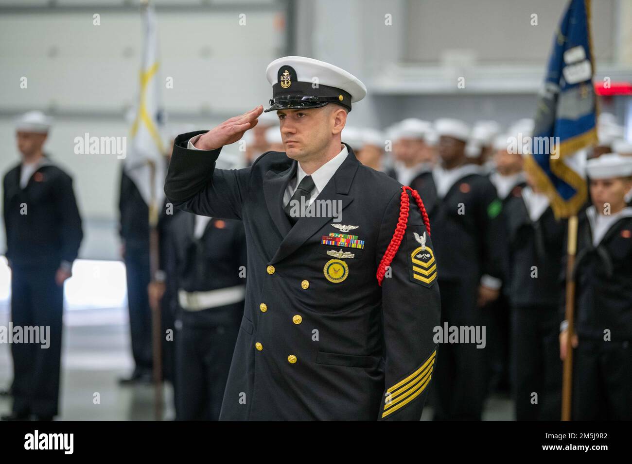 Chief Aviation Structural Mechanic Edison Owen, a recruit division commander, salutes inside Midway Drill Hall during a pass-in-review graduation ceremony at Recruit Training Command. More than 40,000 recruits train annually at the Navy's only boot camp. Stock Photo