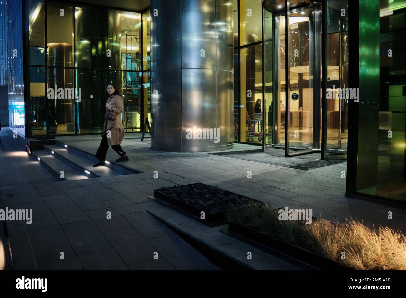 Woman walks out of the Federation Tower in Moscow International Business Centre (MIBC) at night. Moscow, Russia. Stock Photo