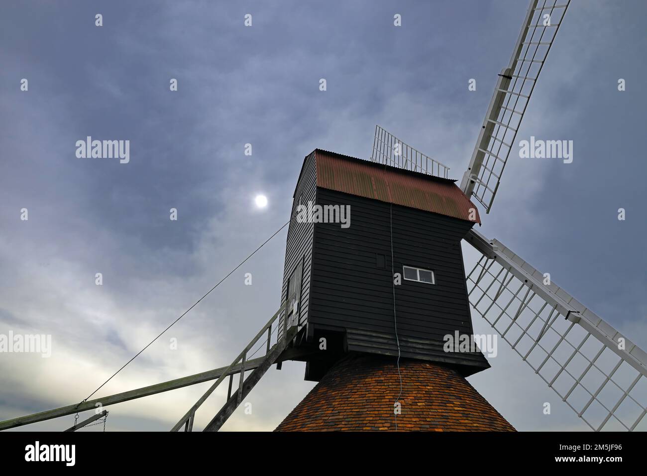 18th century windmill in a field on farmland with sun visible through cloud in the village of Stevington, Bedfordshire, England, UK Stock Photo