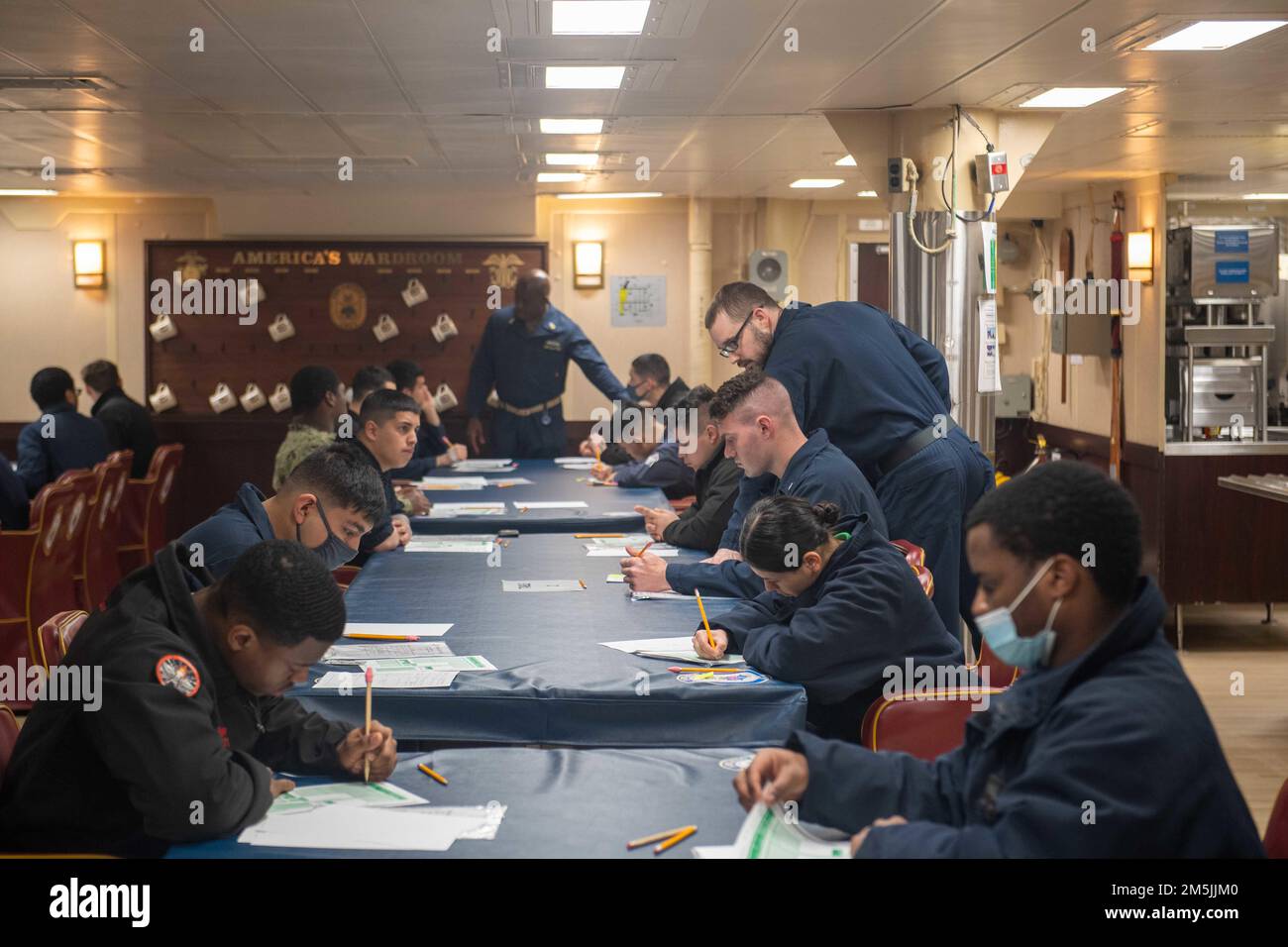 EAST CHINA SEA (March 19, 2022) Sailors assigned to the forward-deployed amphibious assault ship USS America (LHA 6) take the Navy-wide E-5 advancement exam in the ship’s wardroom. America, lead ship of the America Amphibious Ready Group, is operating in the U.S. 7th Fleet area of responsibility to enhance interoperability with allies and partners and serve as a ready response force to defend peace and stability in the Indo-Pacific region, Stock Photo