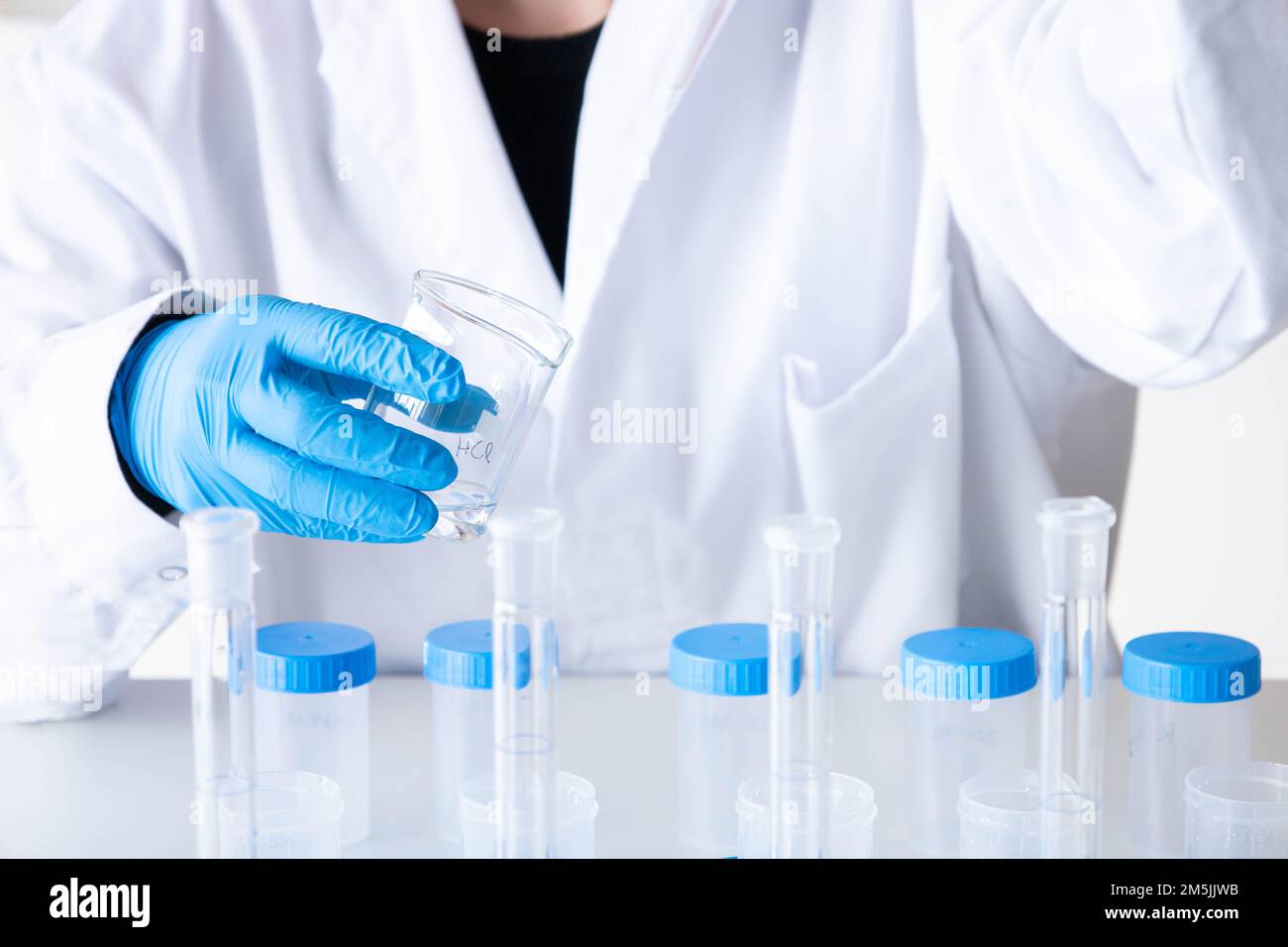 Left handed female scientist analyzing solutions with blue gloves and equipment. Laboratory technician with a pipette. Development and research. Stock Photo