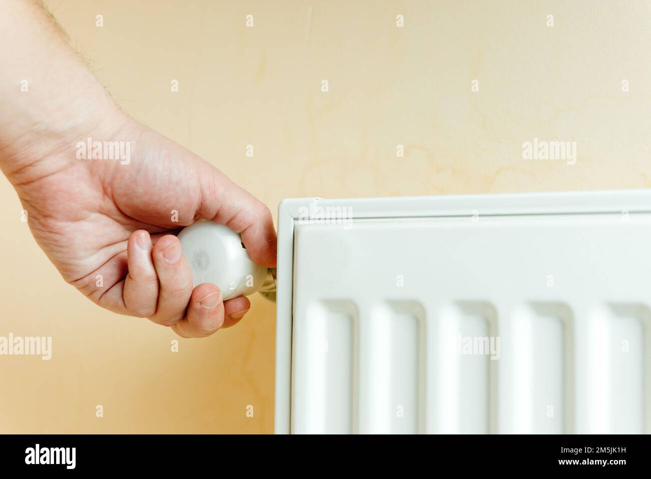 climate optimism and climate Control . A man switches the temperature on the batteries. Saves heat. Protects the environment. Stock Photo