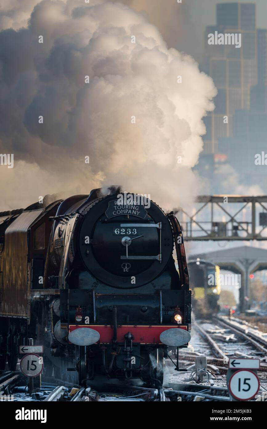 Steam train 46233 Duchess of Sutherland approaching Clapham Junction on a freezing cold December morning, with London skyline in background Stock Photo