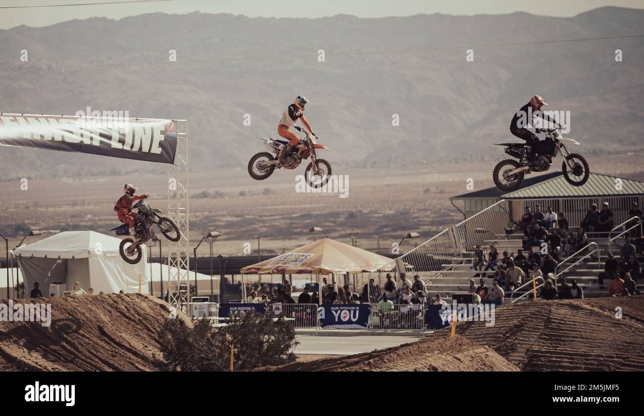 Professional motocross riders cross the finish line during the