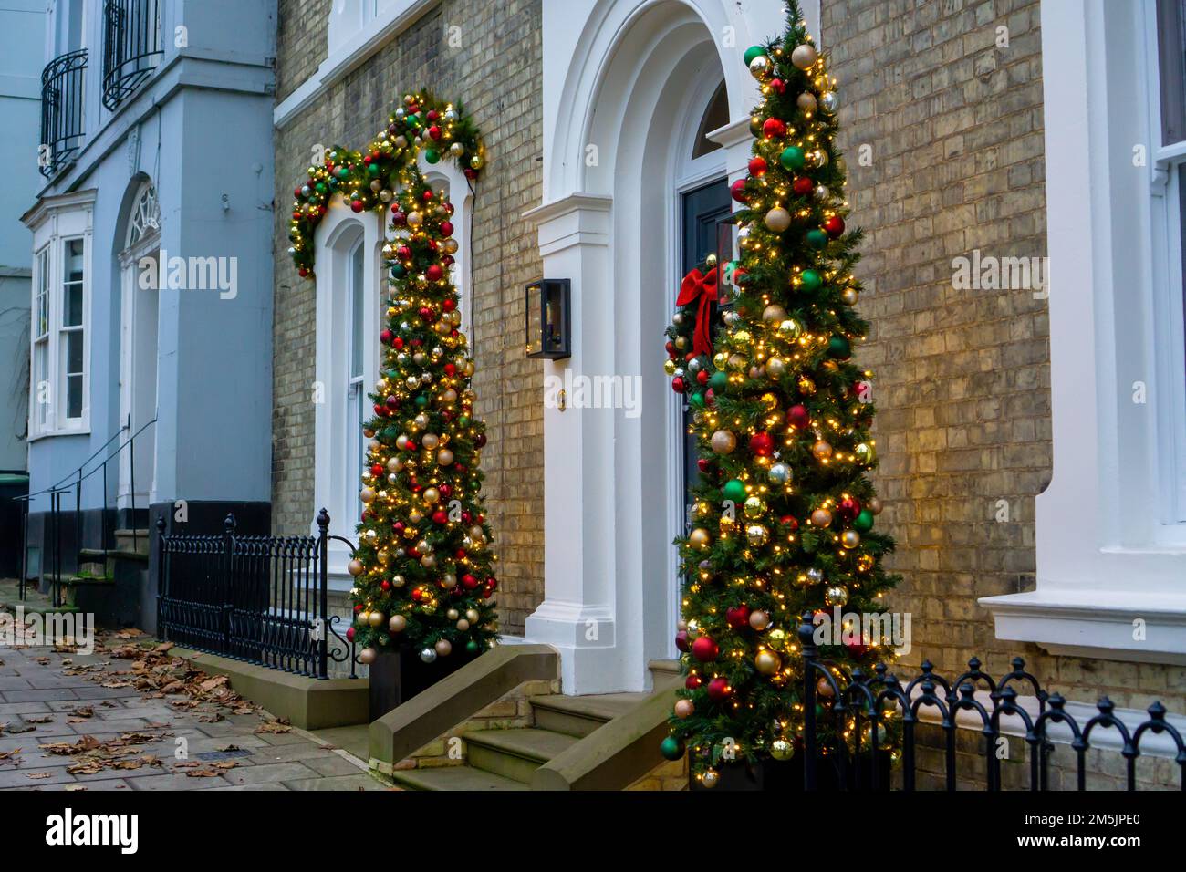 Heavily decorated Christmas trees either side of a building entrance in Saffron Walden, Essex