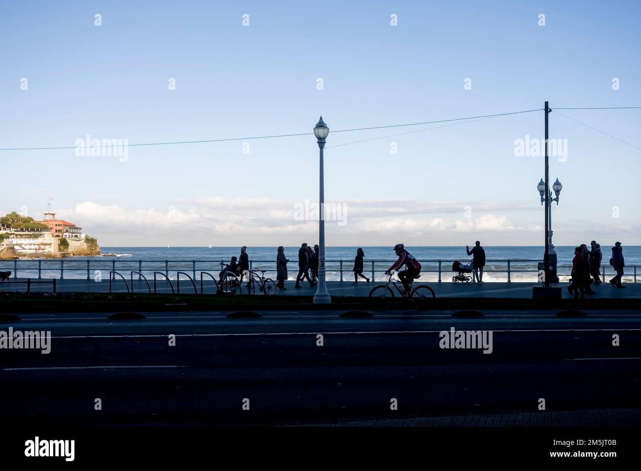 Silhouette view of a group of people walking along the promenade in ...