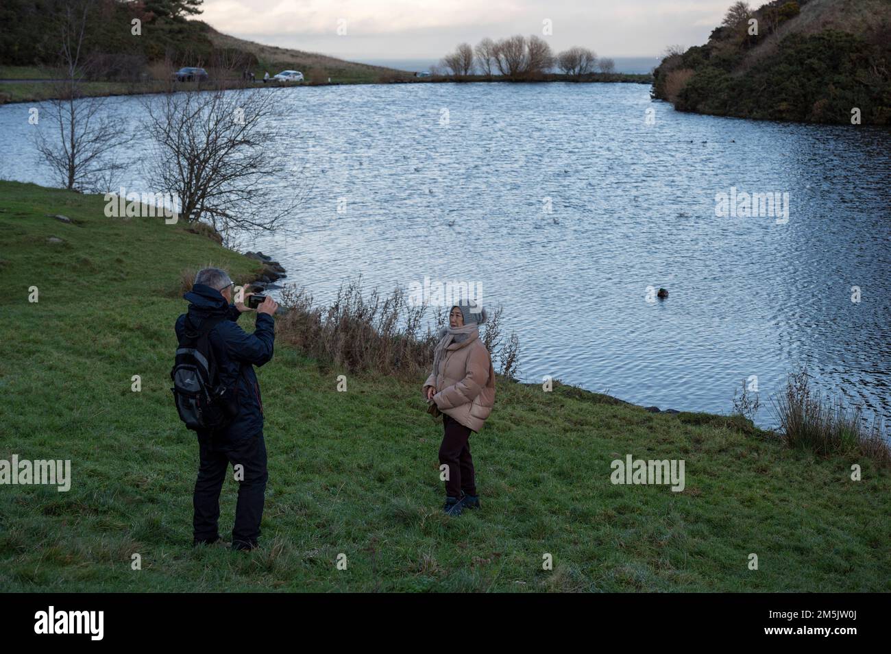 Thursday December 29th 2022: Edinburgh Scotland, UK. Tourists take photos in Holyrood Park beside Dunsapie Loch. Stock Photo