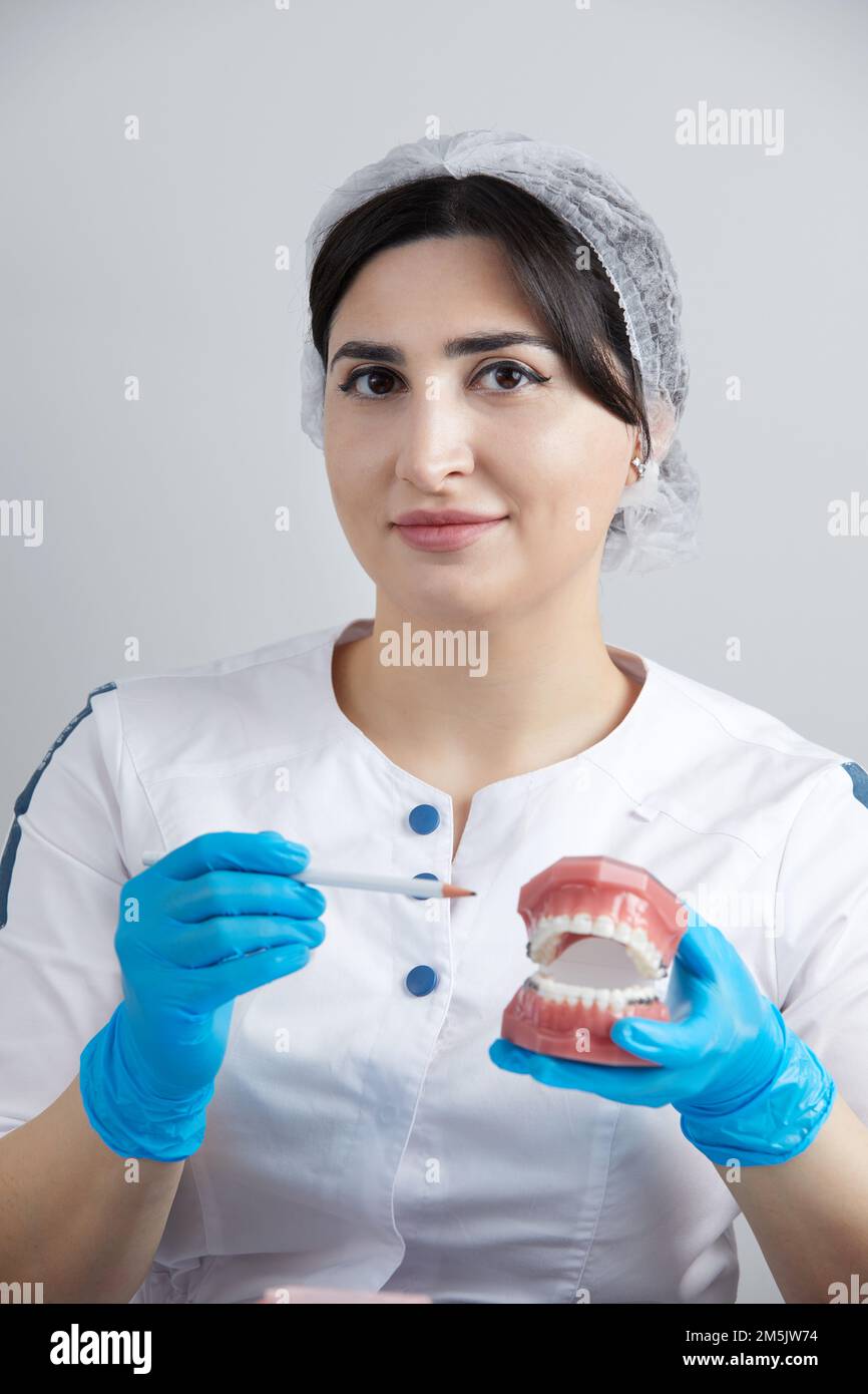 Orthodontist showing model of human jaw with wire braces and aligners