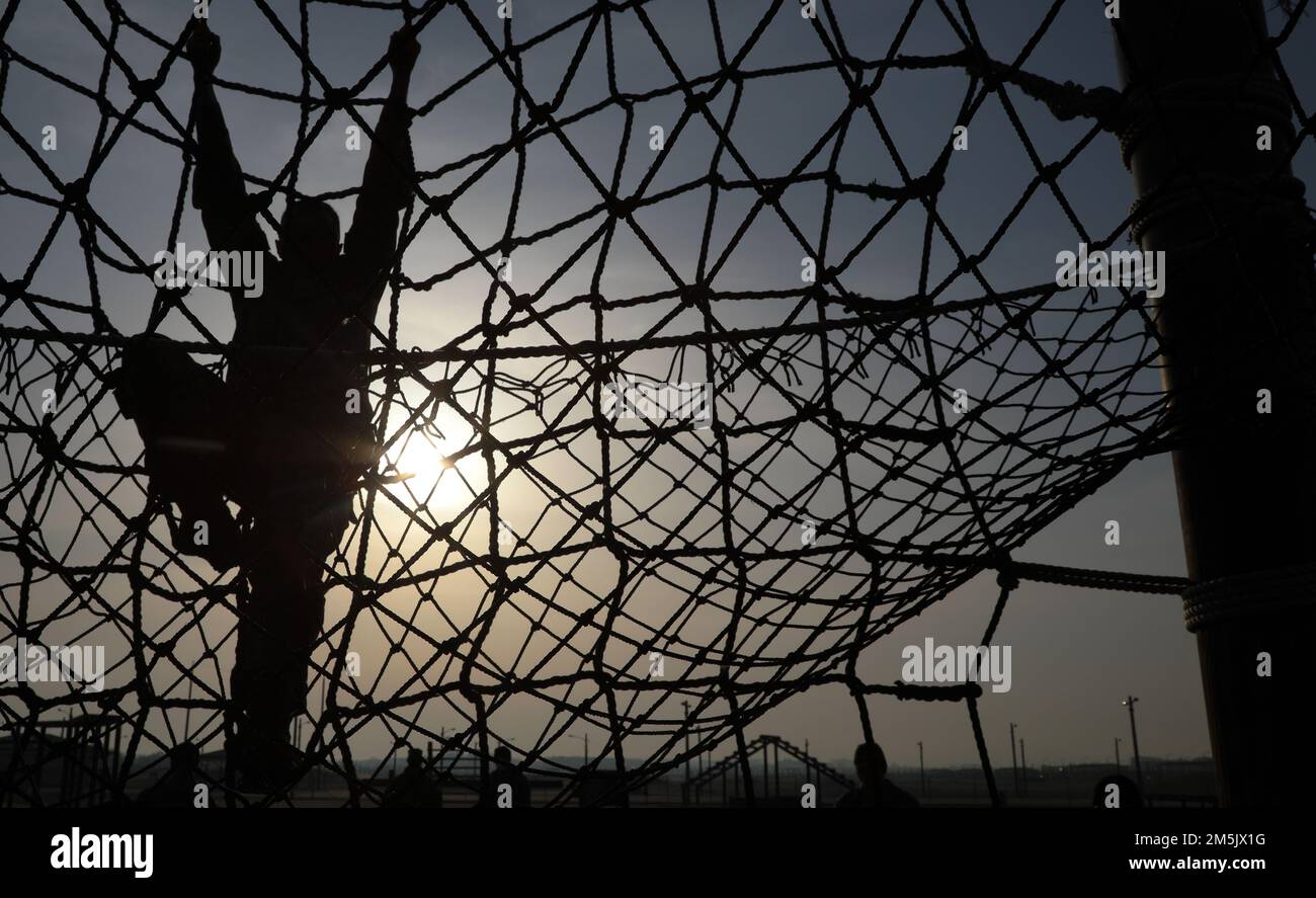 Soldier assigned to the 2nd Combat Aviation Brigade, 2nd Infantry Division, attempts the the net climbing event during the Best Warrior Competition Obstacle Course, 21 Mar. 2022, Camp Humphreys, Republic of Korea. The BWC is held to recognize the best Soldiers of the 2CAB through various tests including a ruck march, obstacle course and a Soldier of the quarter board. Stock Photo