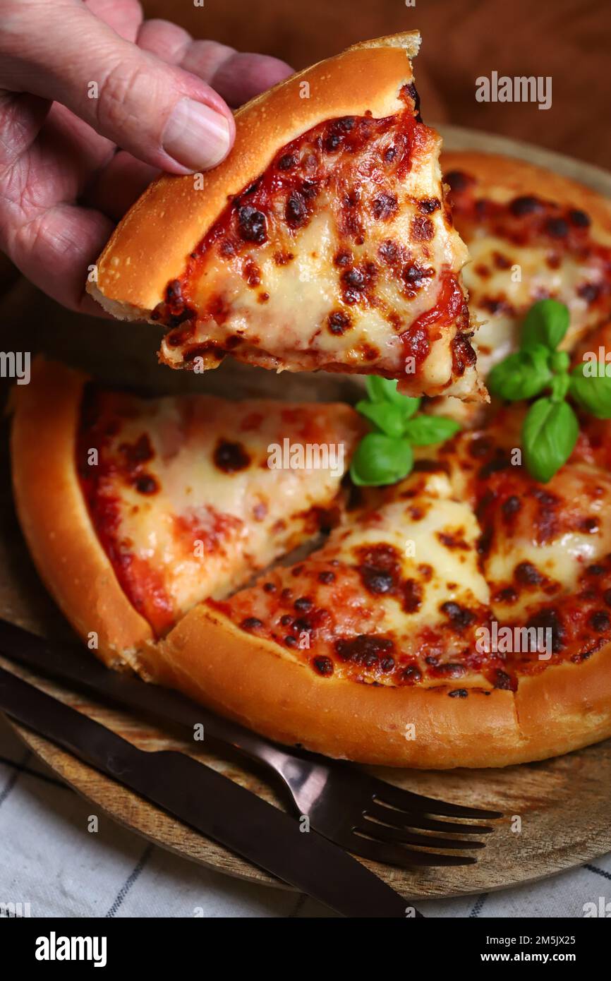 Slice of fresh hot margarita pizza in hand. selective focus Stock Photo