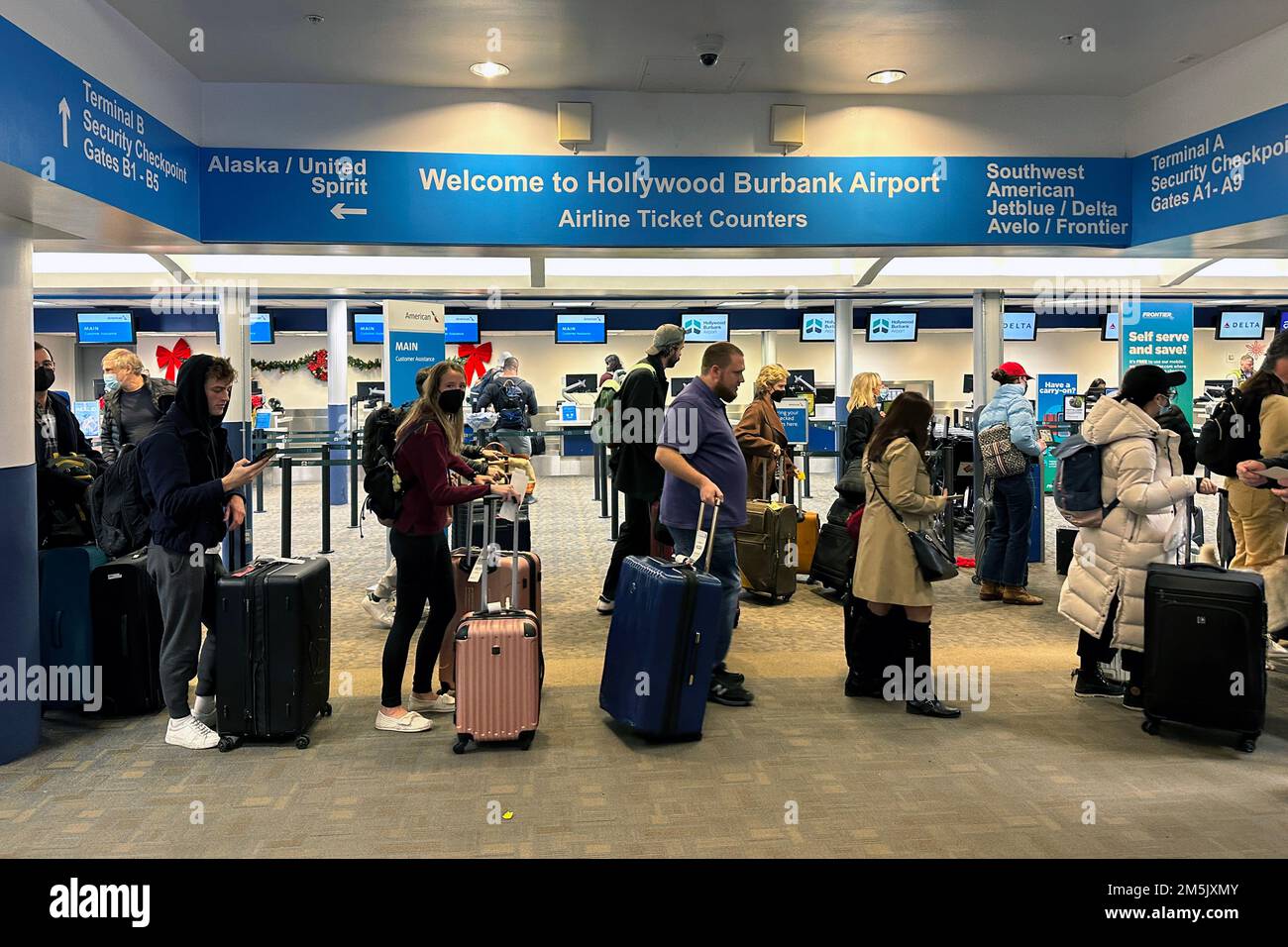 Passengers wait in line to check in luggage at the American, Delta and