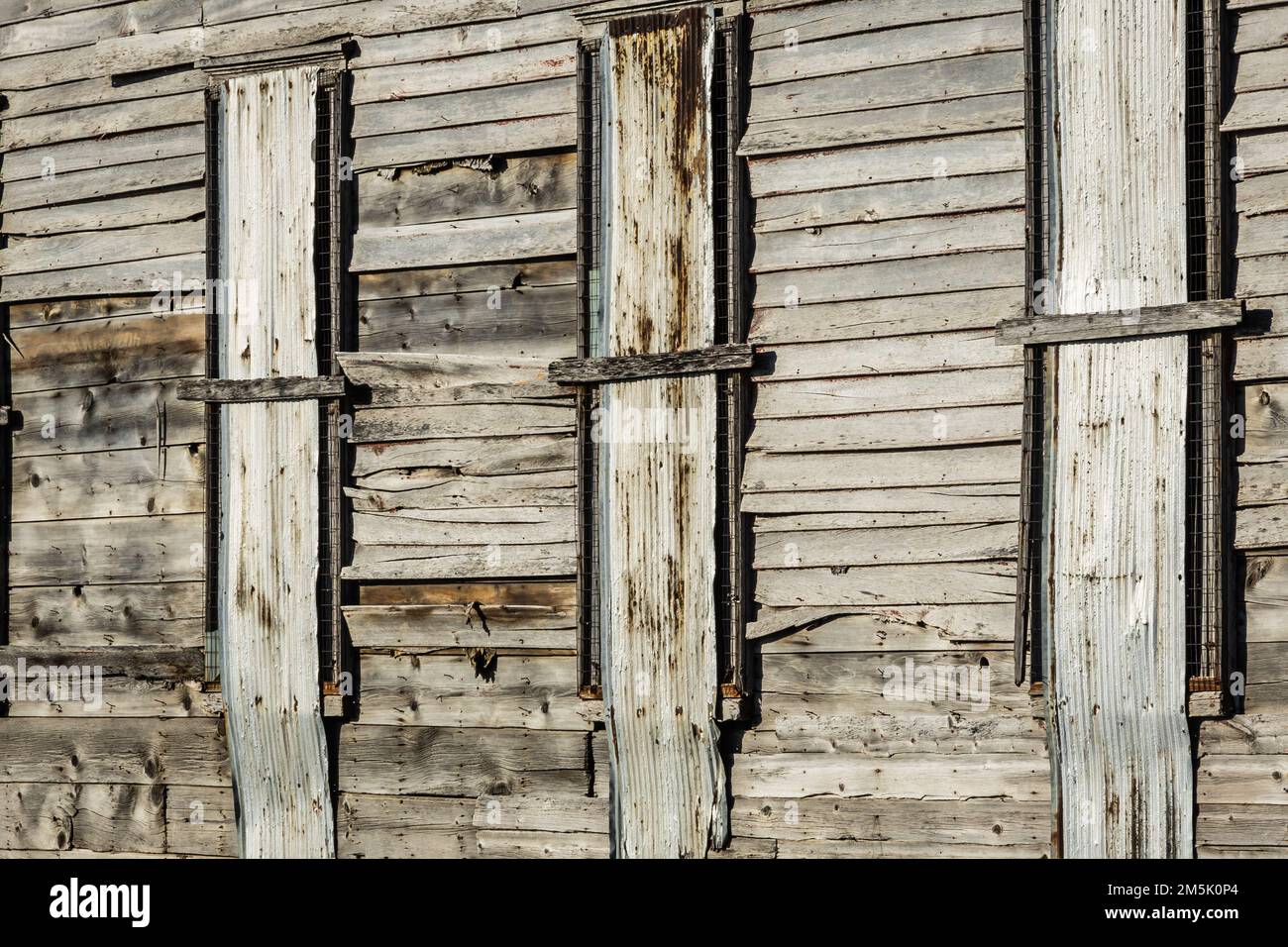 Old wooden siding of a historic structure with its windows covered ...