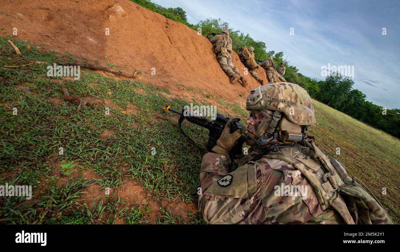 Sgt. Gustavo Mollar-Aybar, Alpha Company, 29th Brigade Engineer Battalion, 3rd Brigade Combat Team, 25th Infantry Division, uses a radio to coordinate squad moves during an air assault, Mar. 22, 2022, Fort Thanarat, Thailand. Air assaults allow troops to rapidly insert near an objective and utilize the element of surprise during the attack. Stock Photo