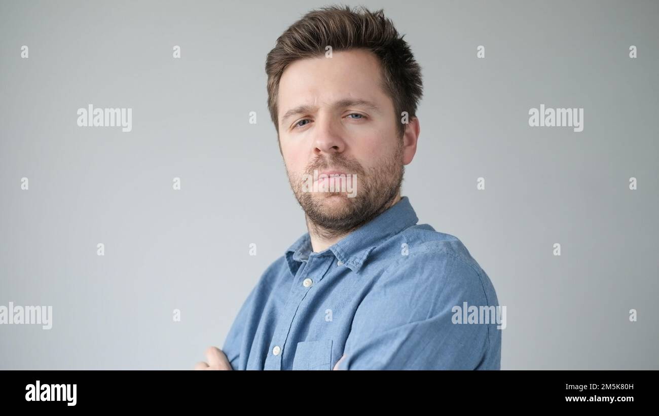 Young handsome man has serious expression poses in studio Stock Photo