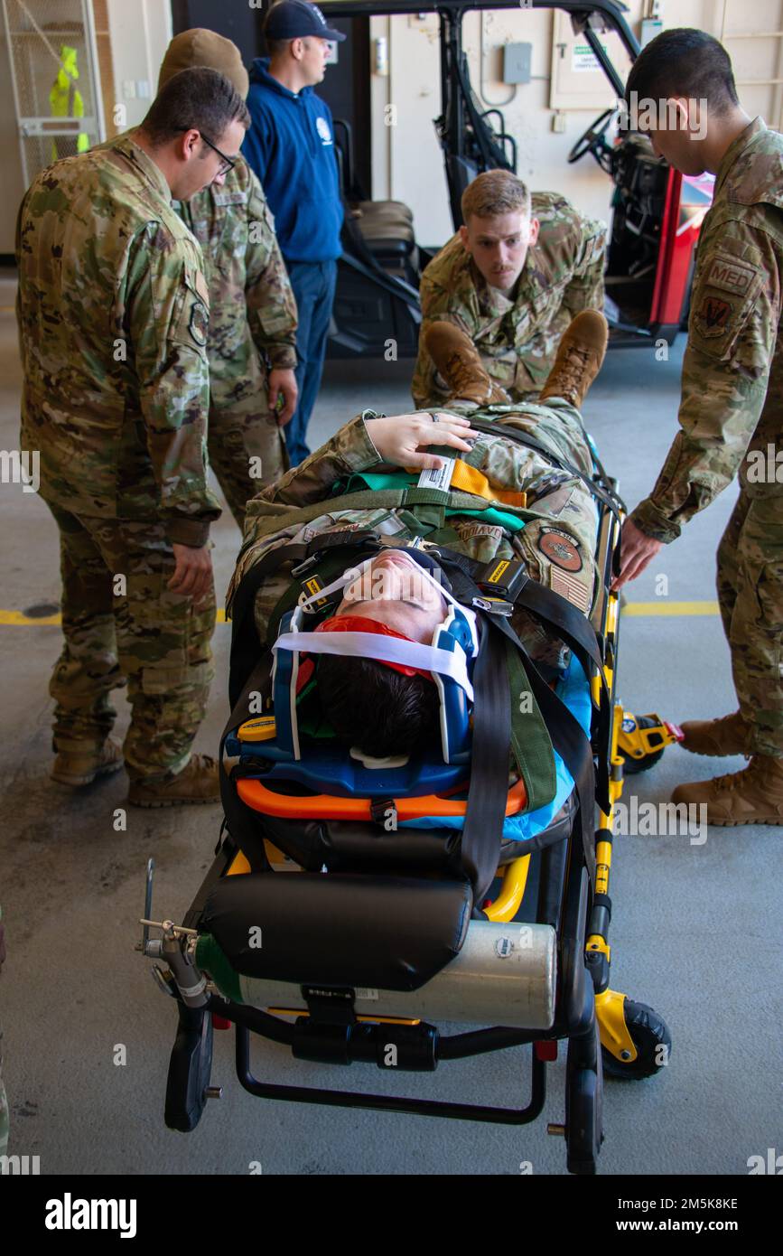 U.S. Airmen with the 325th Civil Engineer Squadron’s Tyndall Fire Department secure a simulated patient to a backboard during an emergency medical technician training course at Tyndall Air Force Base, Florida, March 21, 2022. The 325th Operational Medical Readiness Squadron ambulance services flight assisted the fire department with EMT hands-on and emergency medicine training, expanding their first responder capabilities. Stock Photo