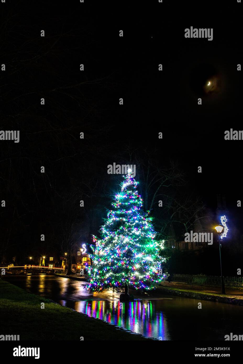 The decorated Christmas tree in the river at BourtonontheWater in the Cotswolds Stock Photo