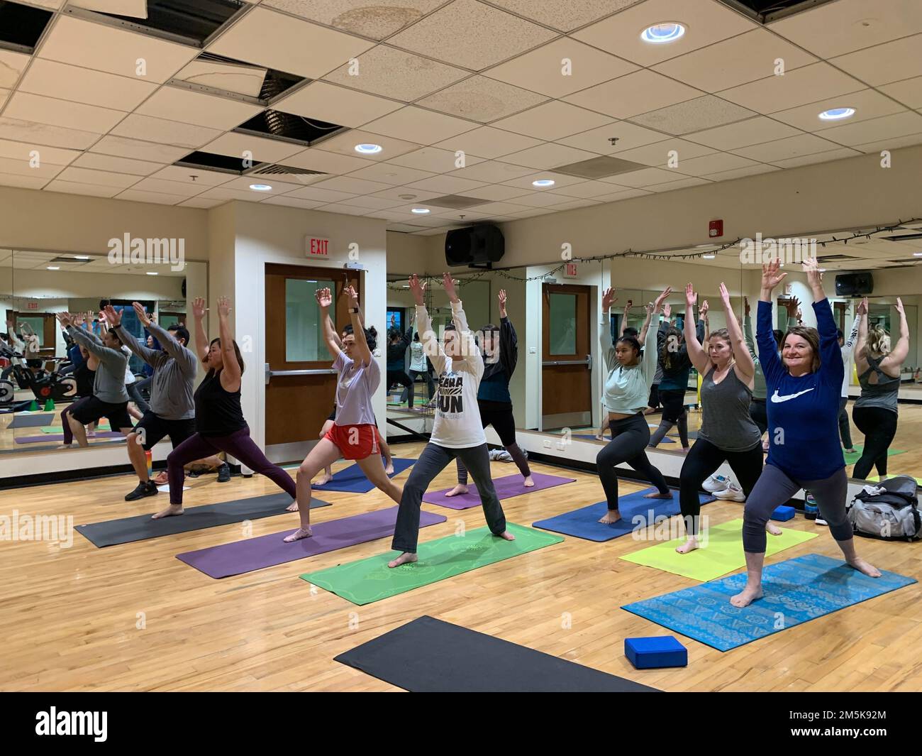 220328-N-UX196-1005 NAVAL AIR STATION SIGONELLA, Italy (March 28, 2022) Students practice warrior pose during a yoga class hosted by Sigonella's Morale, Welfare and Recreation at the Fit District fitness center on Naval Air Station Sigonella, March 28, 2022. NAS Sigonella's strategic location enables U.S., allied, and partner nation forces to deploy and respond as required, ensuring security and stability in Europe, Africa and Central Command. Stock Photo