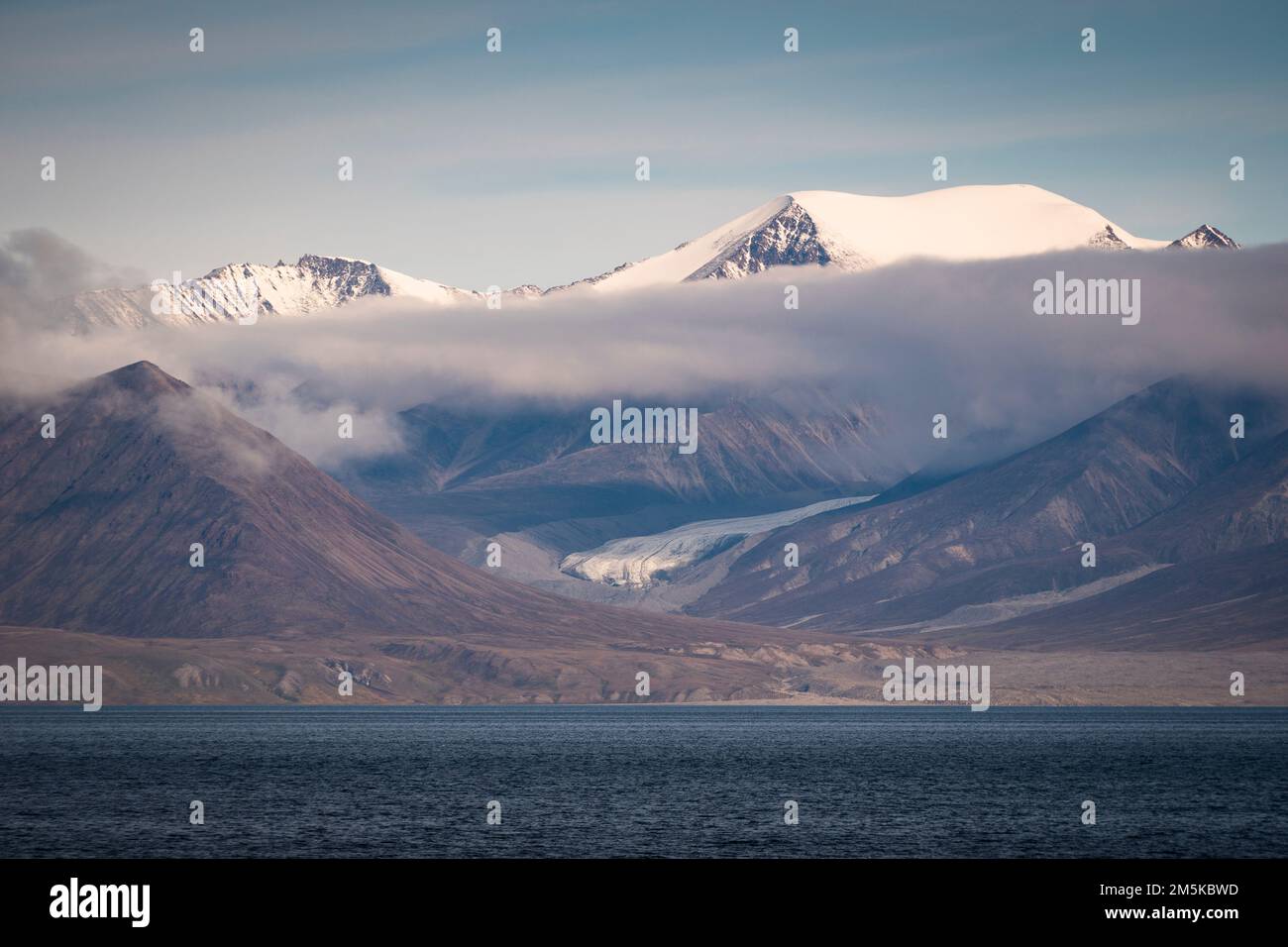 Glacier decending from the mountains of Bylot Island to meet the sea in Nunavut, Canada. Stock Photo