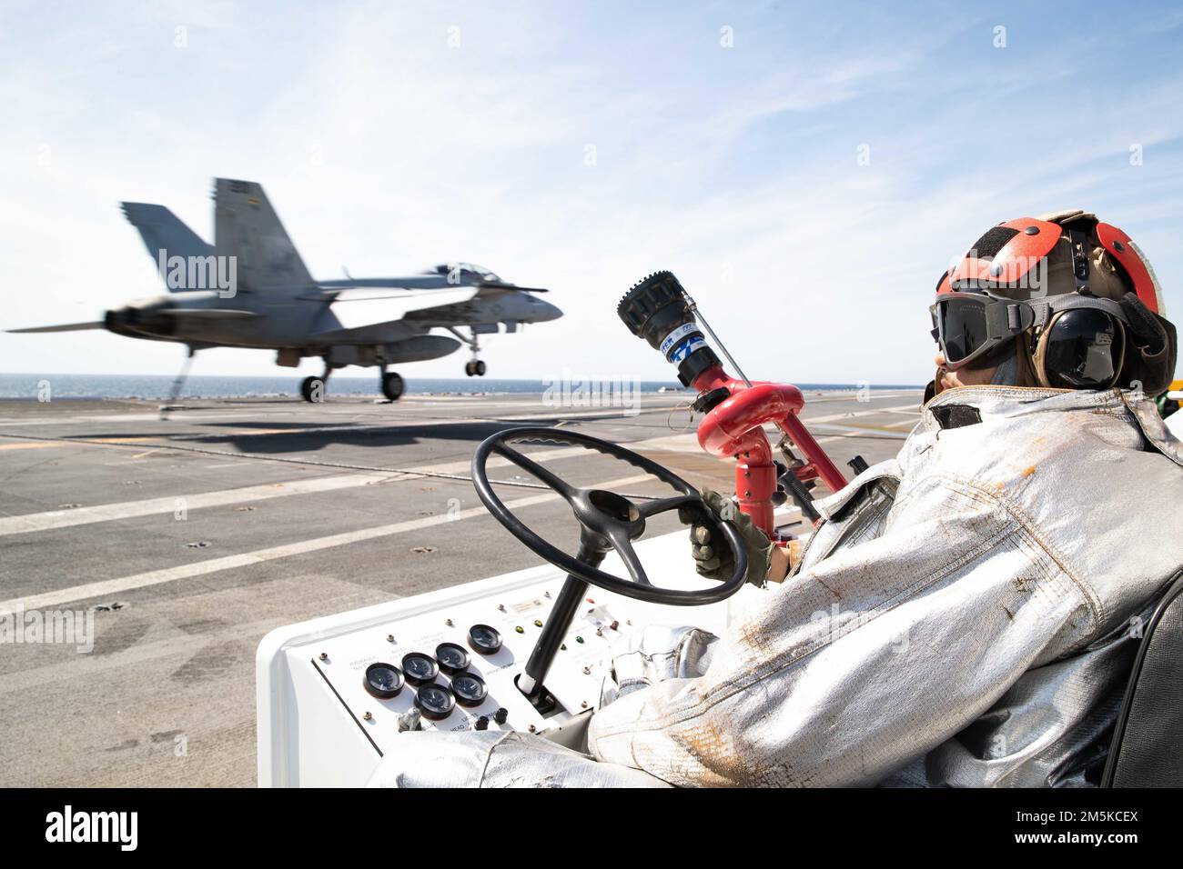 Aviation Boatswain's Mate (Handling) Airman Nathaniel Williams, from Bay City, Michigan, assigned to USS Gerald R. Ford's (CVN 78) air department, mans a P-25 fire truck as an F/A-18F Super Hornet attached to the 'Blacklions' of Strike Fighter Squadron (VFA) 213 lands on the flight deck, March 22, 2022. Ford is underway in the Atlantic Ocean conducting flight deck certification and air wing carrier qualification as part of the ship’s tailored basic phase prior operational deployment. Stock Photo