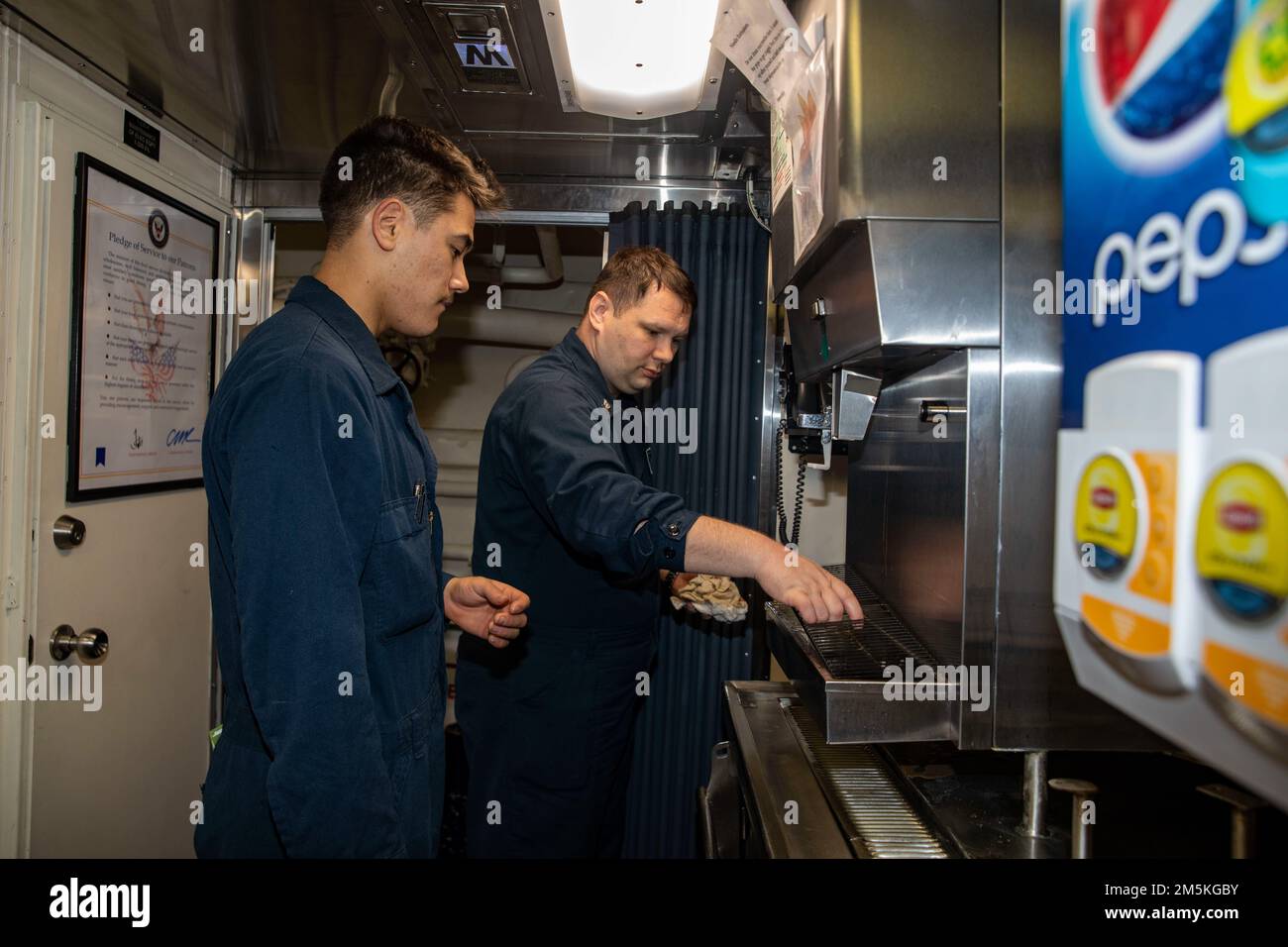 SOUTH CHINA SEA (March 22, 2022) Gas Turbine Systems Technician (Mechanical) Fireman Caiden Haugh (left), from Dallas, and Culinary Specialist 1st Class Ricky Beamis (right), from Indianapolis, conduct maintenance on the water dispenser in the mess deck aboard Arleigh Burke-class guided-missile destroyer USS Ralph Johnson (DDG 114). Ralph Johnson is assigned to Task Force 71/Destroyer Squadron (DESRON) 15, the Navy’s largest forward-deployed DESRON and the U.S. 7th fleet’s principal surface force. Stock Photo