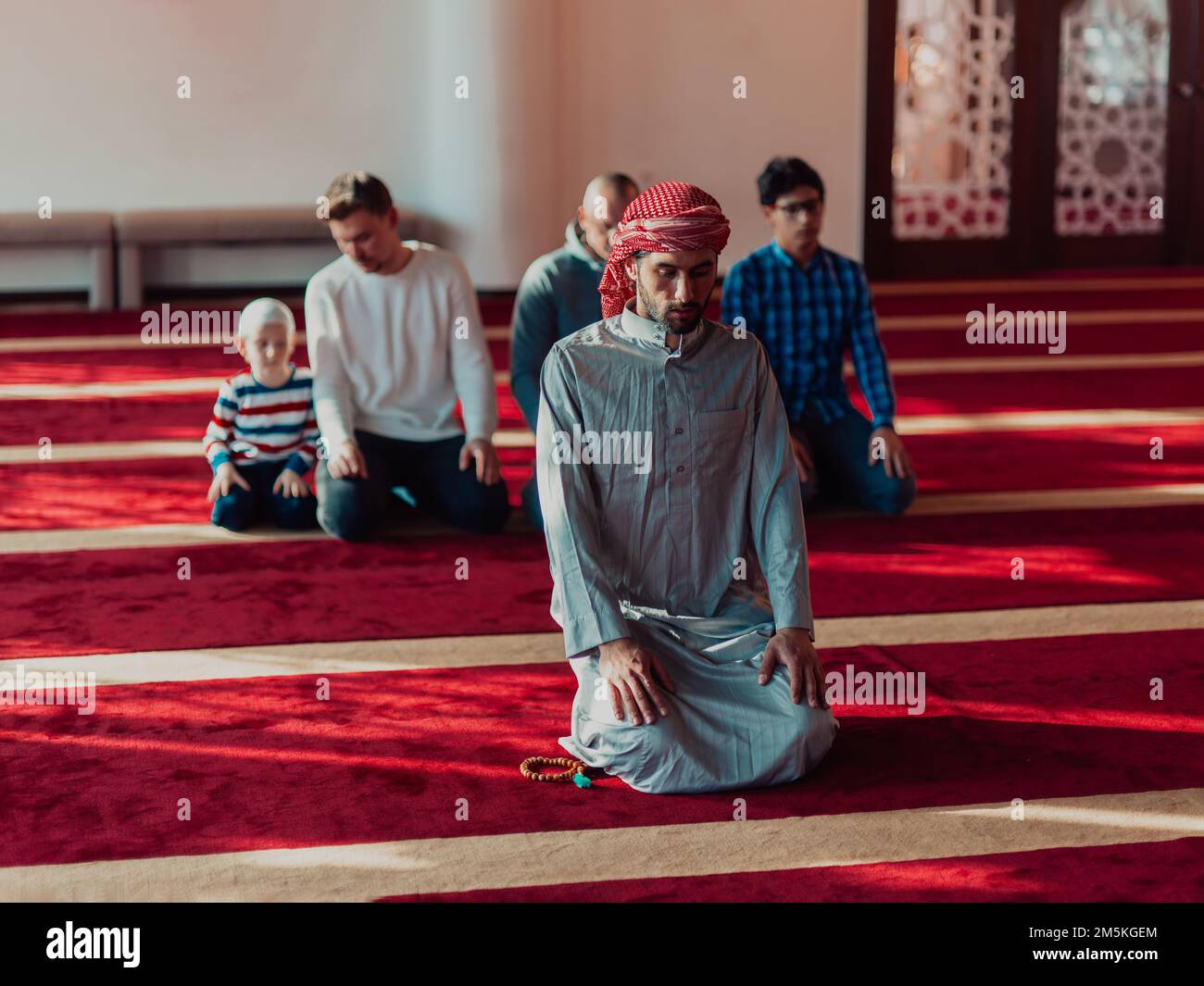 A group of Muslims in a modern mosque praying the Muslim prayer namaz ...