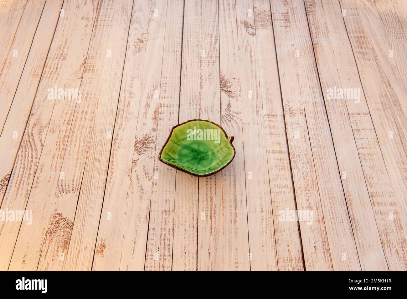 A pretty leaf green dip dish in the center of a wooden plank table Stock Photo