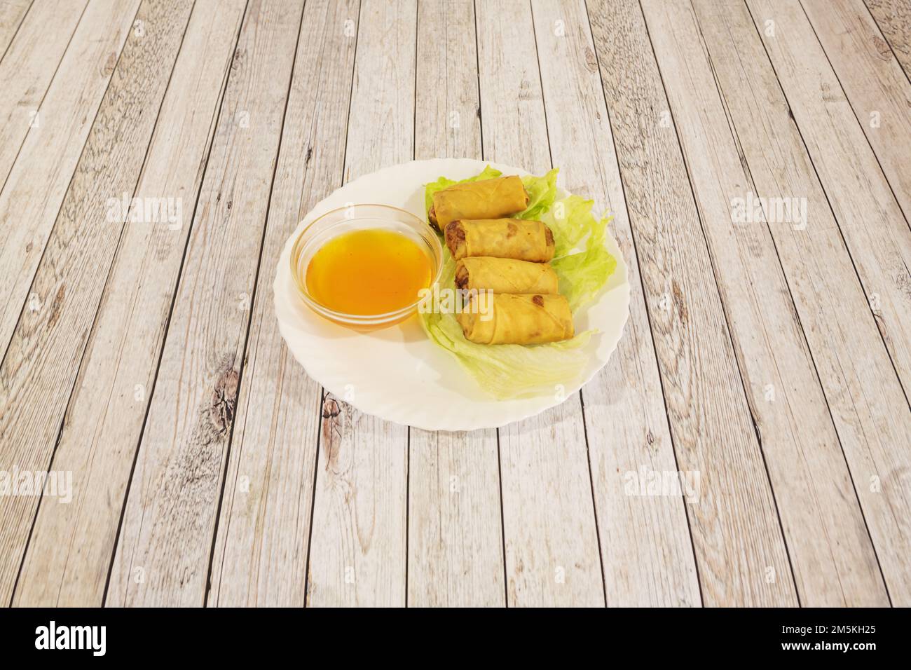 Small fried Thai spring rolls on a lettuce leaf and with dipping sauce Stock Photo