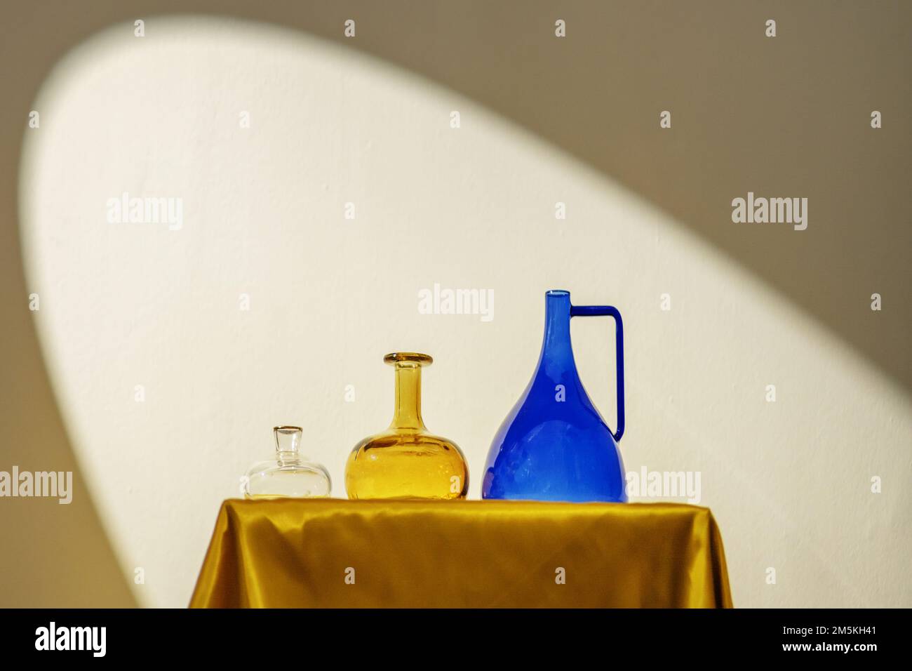 Decorative glass jars of different colors on a golden fabric structure